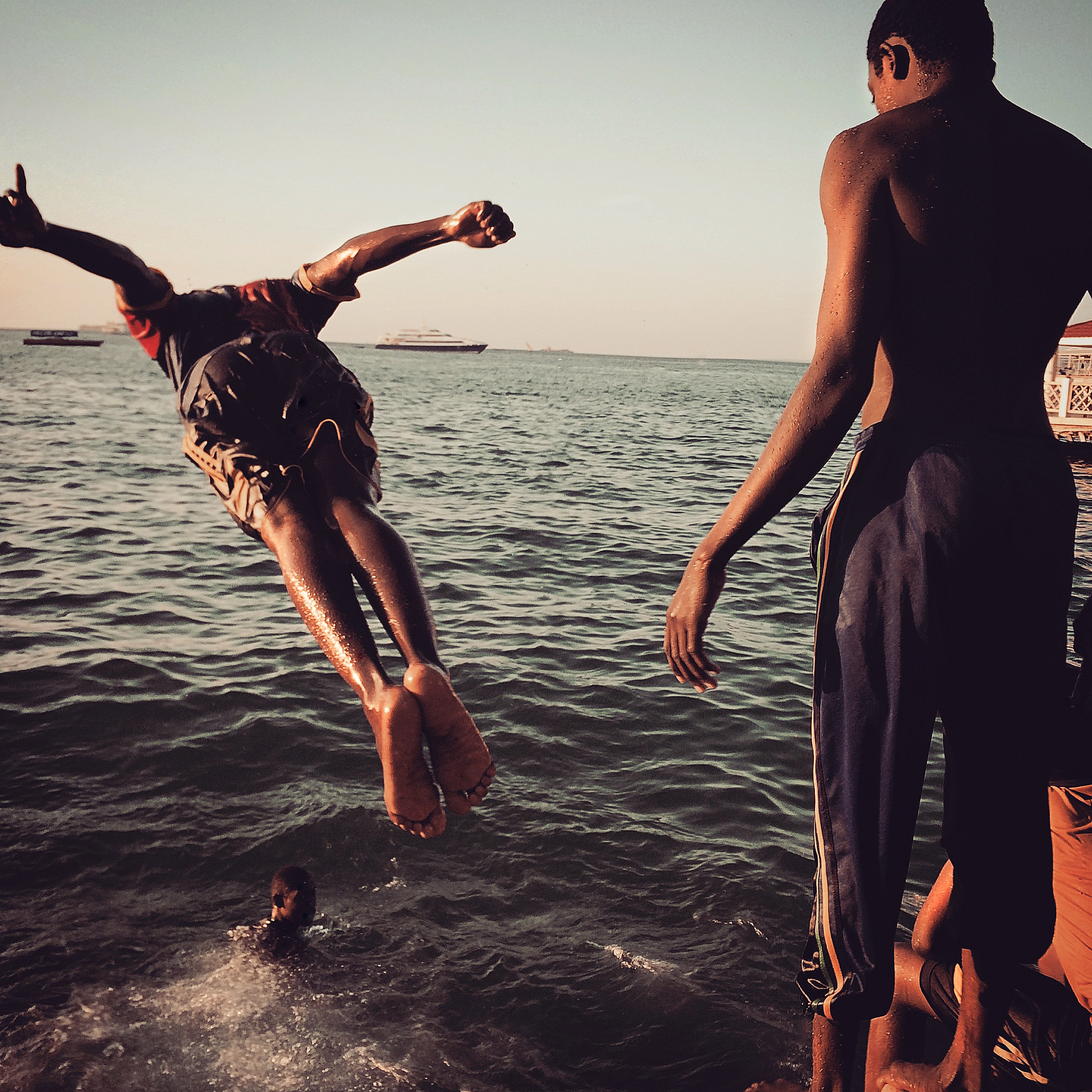  Teens dive into the ocean at sunset  Stone Town, Zanzibar 