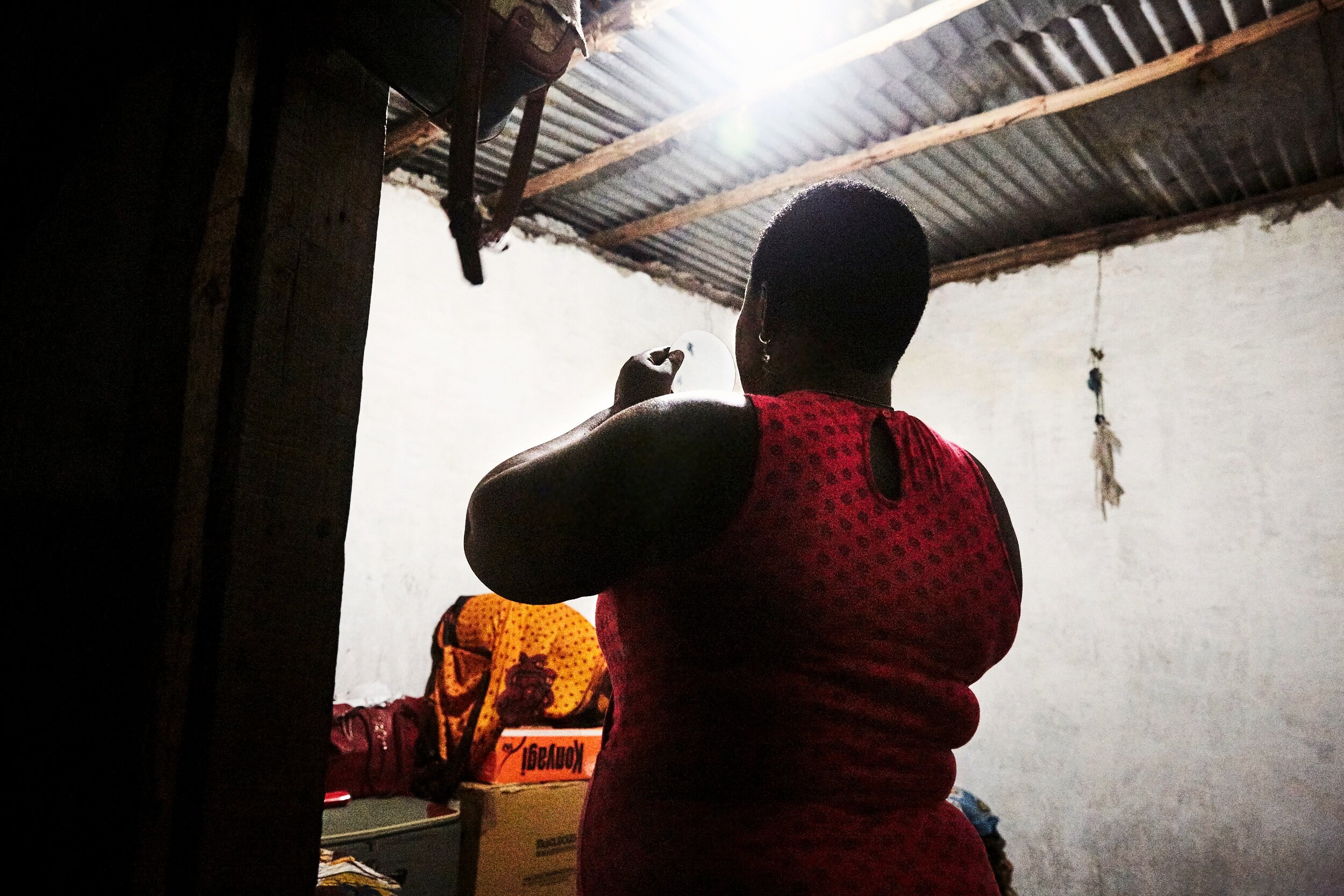  Adama Charles, 29, puts on makeup before the Saturday evening rush.  She came to Zanzibar 3 months ago hoping to work with tourists but ended up in a local brothel. She is routinely criticized by shopkeepers in the villages, so now wears a hijab whe