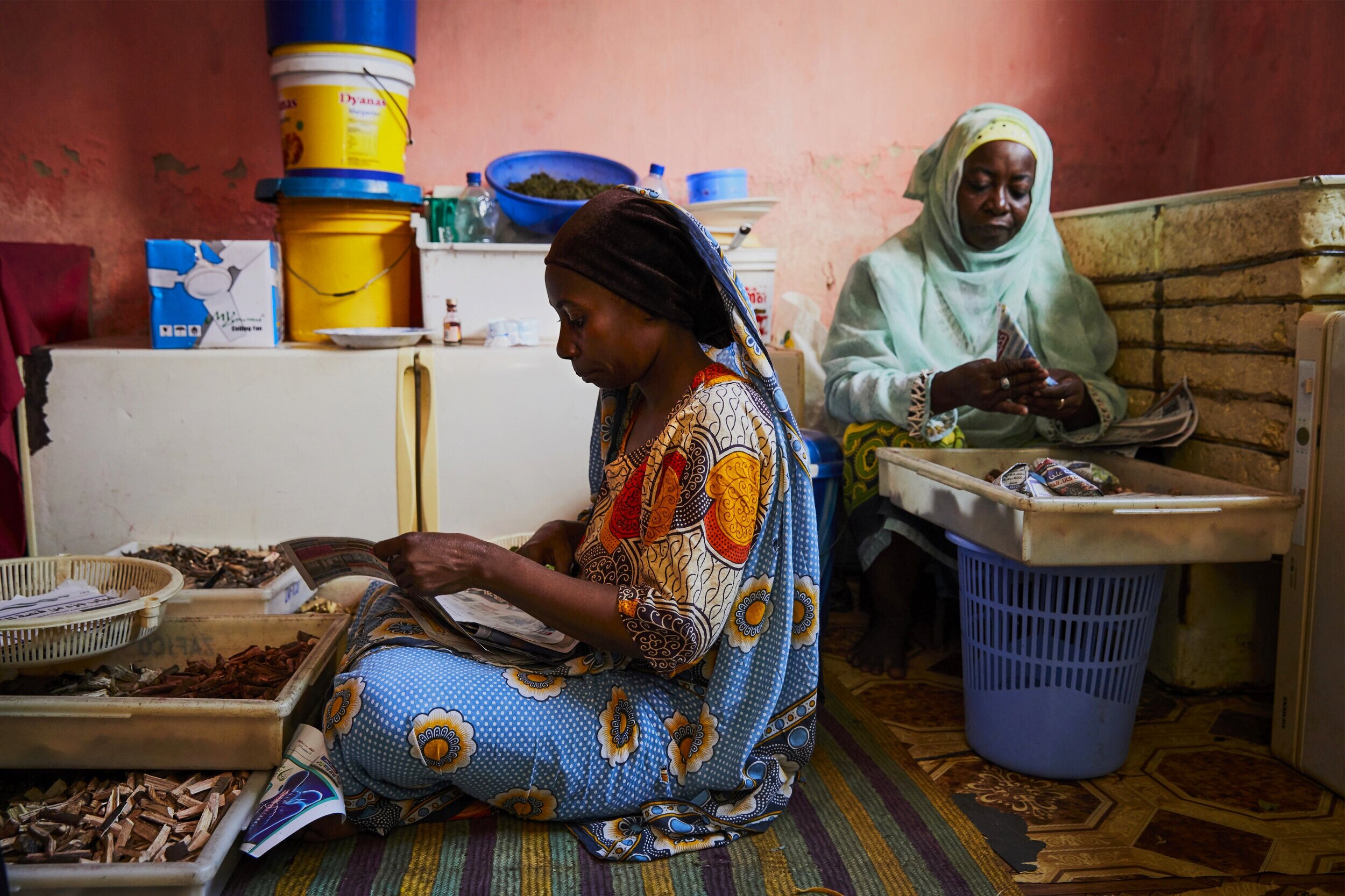  Two assistant healers at Mwanahija Mzee’s traditional clinic, use newspapers to package correct portions of healing herbs and medicinal roots that will be given to patients later in the day. Tufaa Abeid (left) mainly acts as the pharmacist doling ou