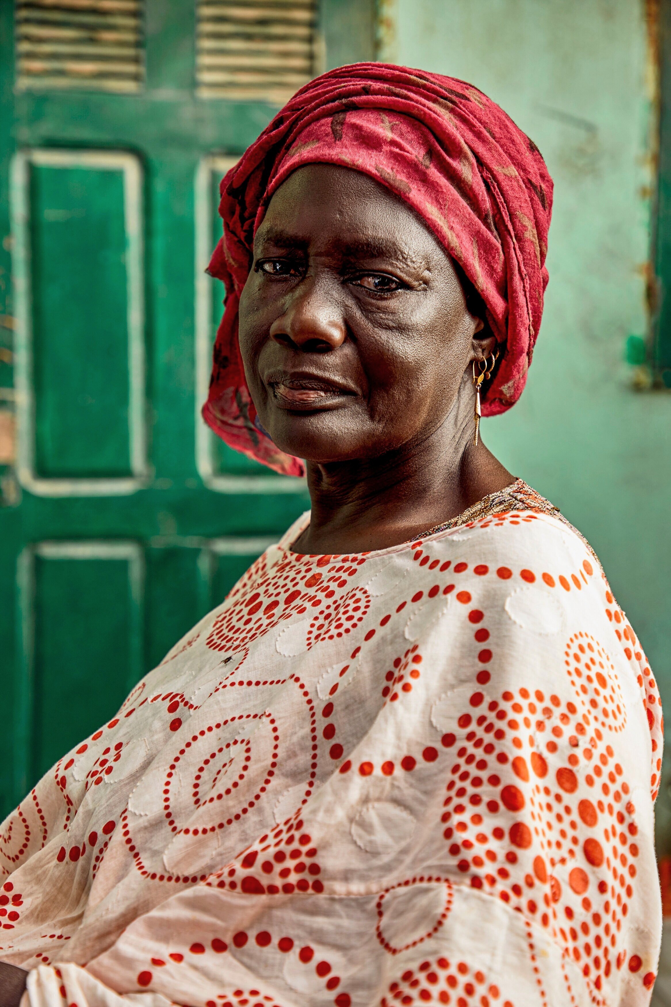  A portrait of Mari Taw, 58 years old, in front of her home, which has been in her family for more than 4 generations. The house, which she shares with her two adult sons and their families, is barely habitable, as the walls and stairway have begun t