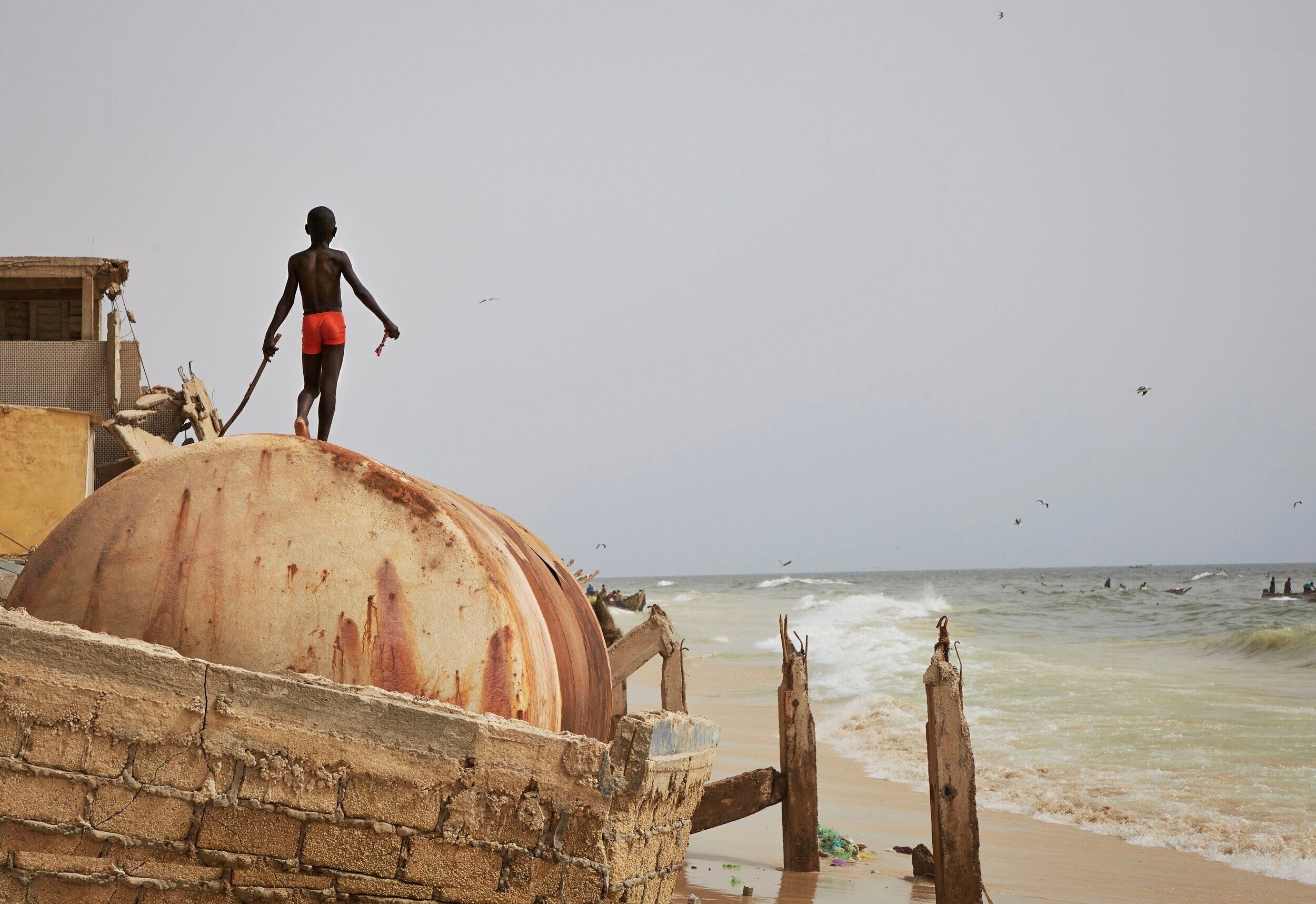  A child plays on the ruins of a sea wall after the ocean surge.  Saint Louis, Senegal 