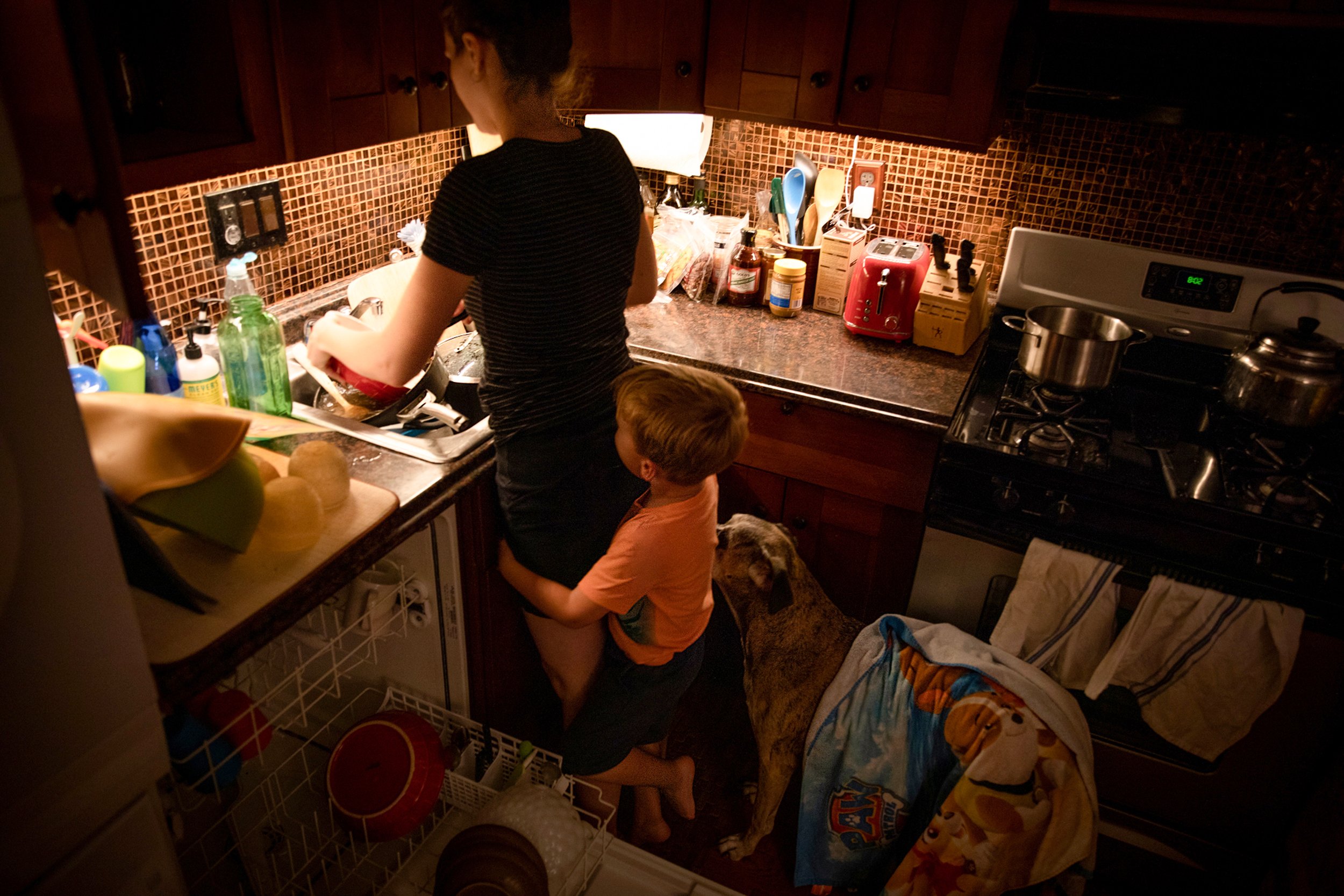  Kathy Reese, attempts to wash the dinner pots, while her 4 year old son David, hugs her legs and dog, Bella waits to be fed at their home in Washington DC.Kathly is the primary care giver for her son , while maintaining a 40 hour work week from home