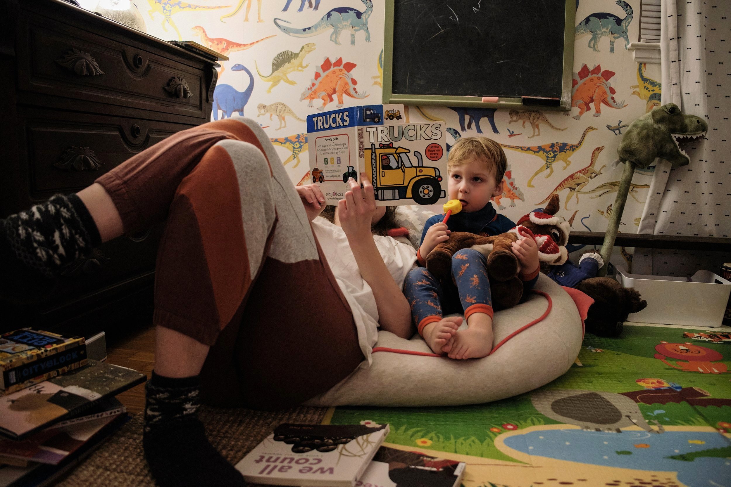  Kathy sits on the floor reading the 4th bedtime book in a row, to her 3 year old son, David. Due to the Covid-19 pandemic, Kathy has no childcare help, as even daycares were closed. She feels intensely bad for her child who does not have any playmat