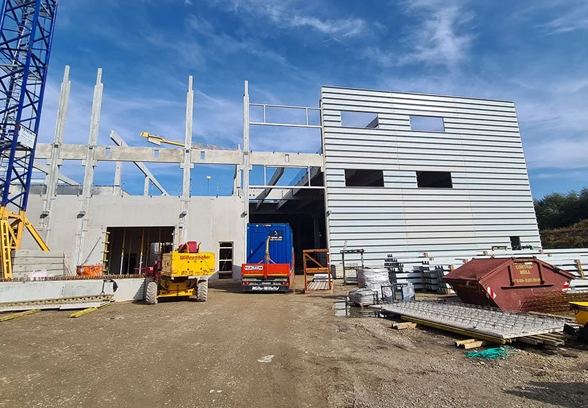  Am nordwestlichen Stadtrand von München in Flughafennähe wurde eine Produktionshalle für einen Automobilkonzern errichtet.  Der zweigeschossige Stahlbetonskelettbau ist mit einer vorgehängten Aluminiumfassade verkleidet.  Eine Stahlkonstruktion träg
