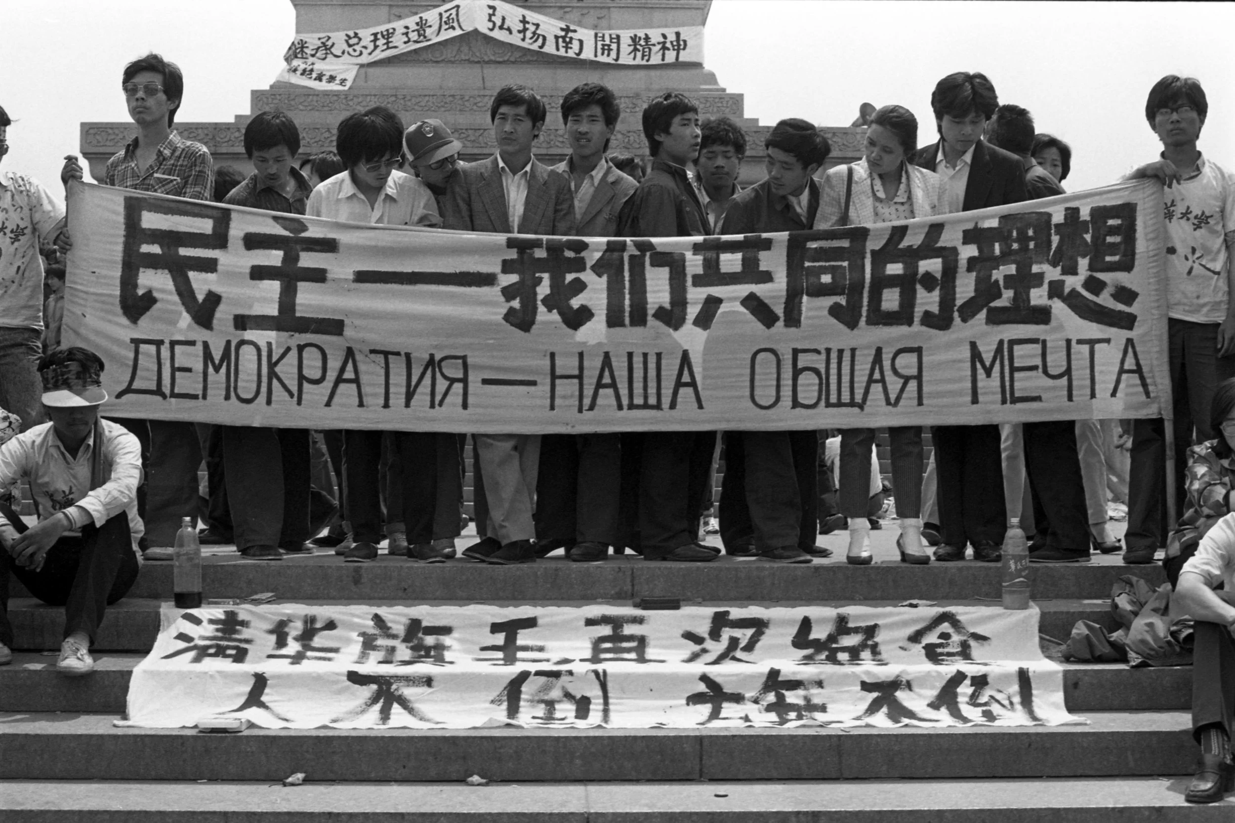 Protesters in front of the Monument to the People's Heroes hold a banner reading “Democracy is our shared aspiration” in Simplified Chinese and Russian. Timed to coincide with Mikhail Gorbachev’s visit to Beijing in mid-May. Photo taken on May 16, 1989. Photo credit: Hsieh San-tai, Howling 1989.