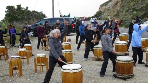 Taiko drummers drumming in open lot.