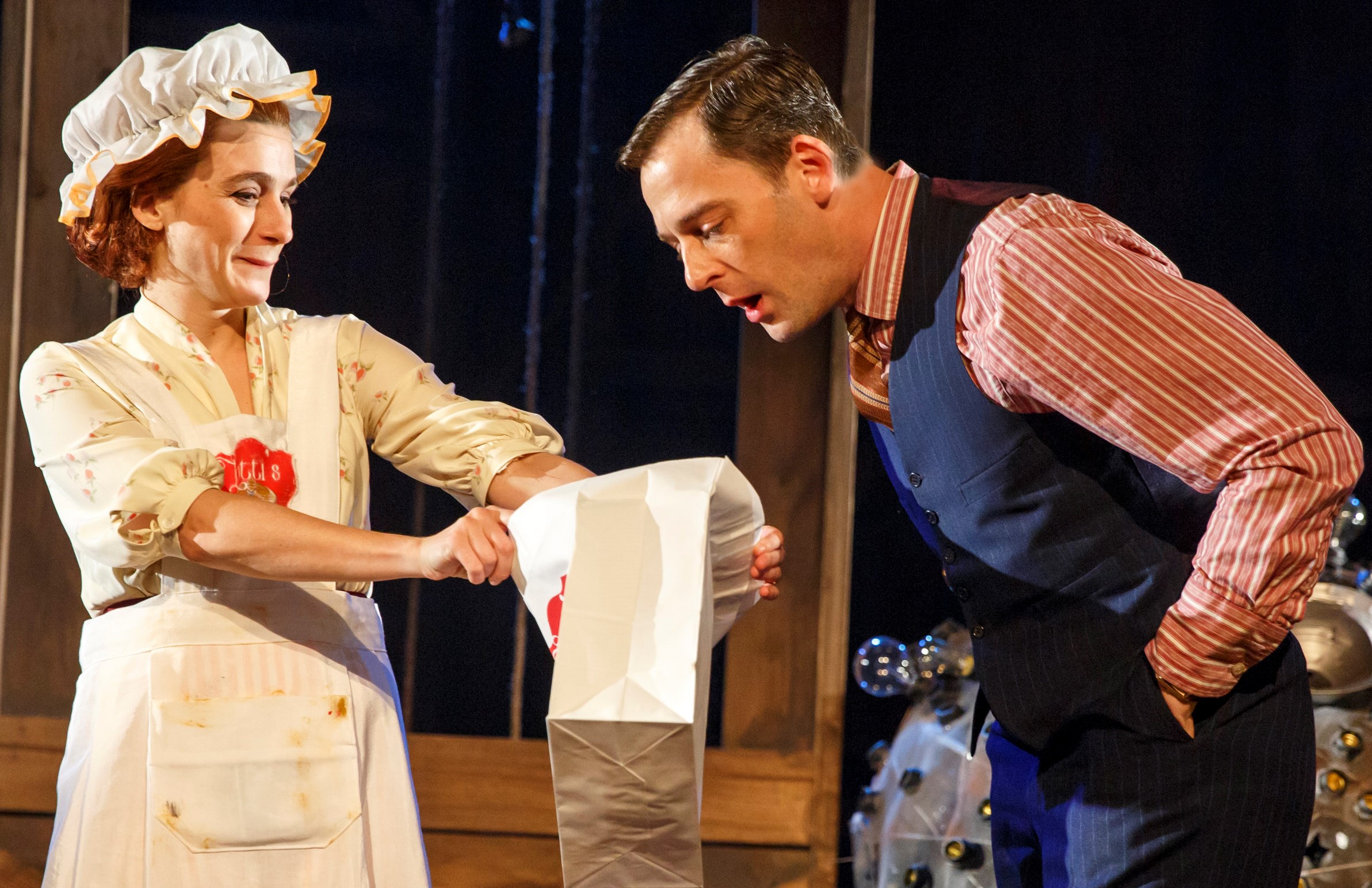 Ruth (Aya Cash) shows her husband Lou (Ken Barnett) pancakes she has brought home from the 1933 world's fair, in the Debate Society's The Light Years . Top, from left: Rocco Sisto as Steele MacKaye, Cash as Adeline, and Erik Lochtefeld as Hillary, with the Mooncart.
