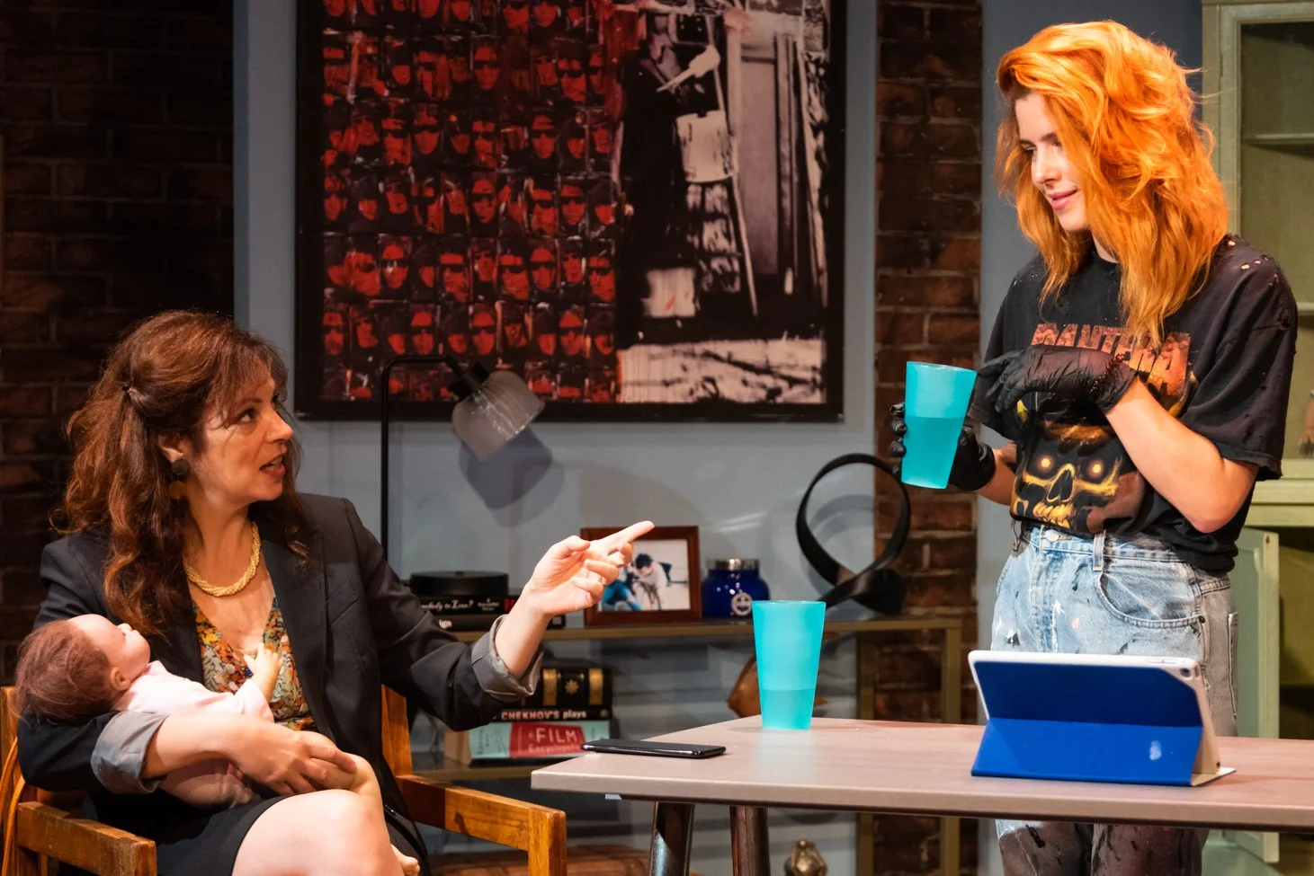 Emily (played by Lori Triolo) cradles Baby Eva while quizzing Kelly (Emily Bett Rickards), Baby Eva’s creator, about her morning consumption of vodka in Reborning by Zayd Dohrn.
