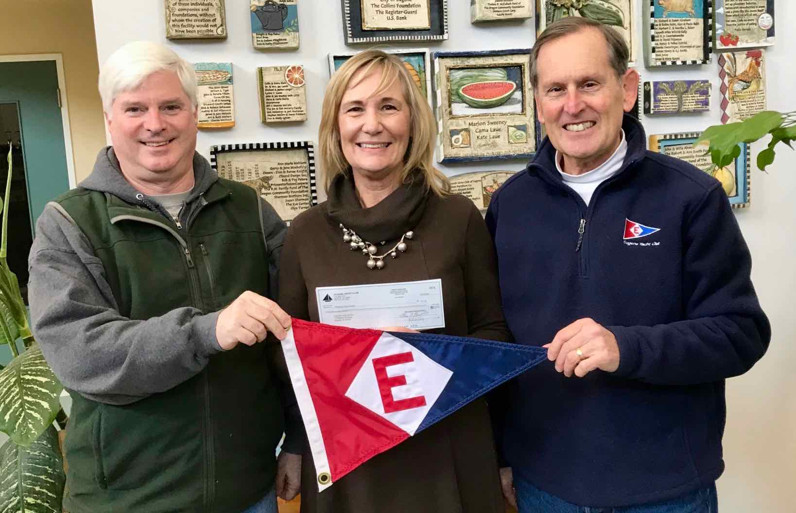  Club Manager Rich Aaring (left) and Rear Commodore Gary Powell (right) present a check and the EYC burgee to Food for Lane County’s Executive Director Beverlee Potter 