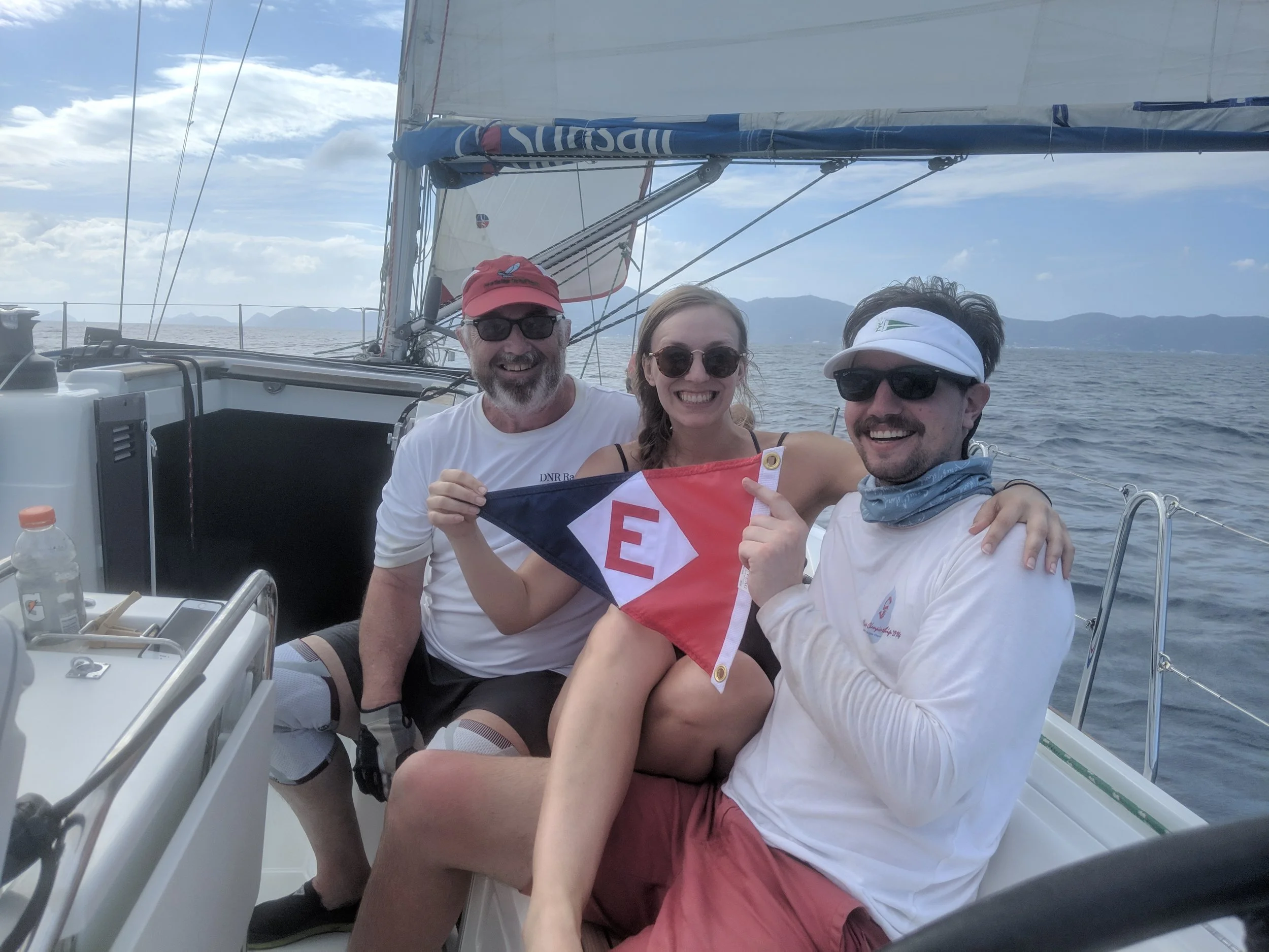 Chris Thomas, Kimi Schler, and Jac Thomas, members of the DNR Racing team, take a moment from training for the Spring Regatta in the British Virgin Islands to hoist the EYC burgee