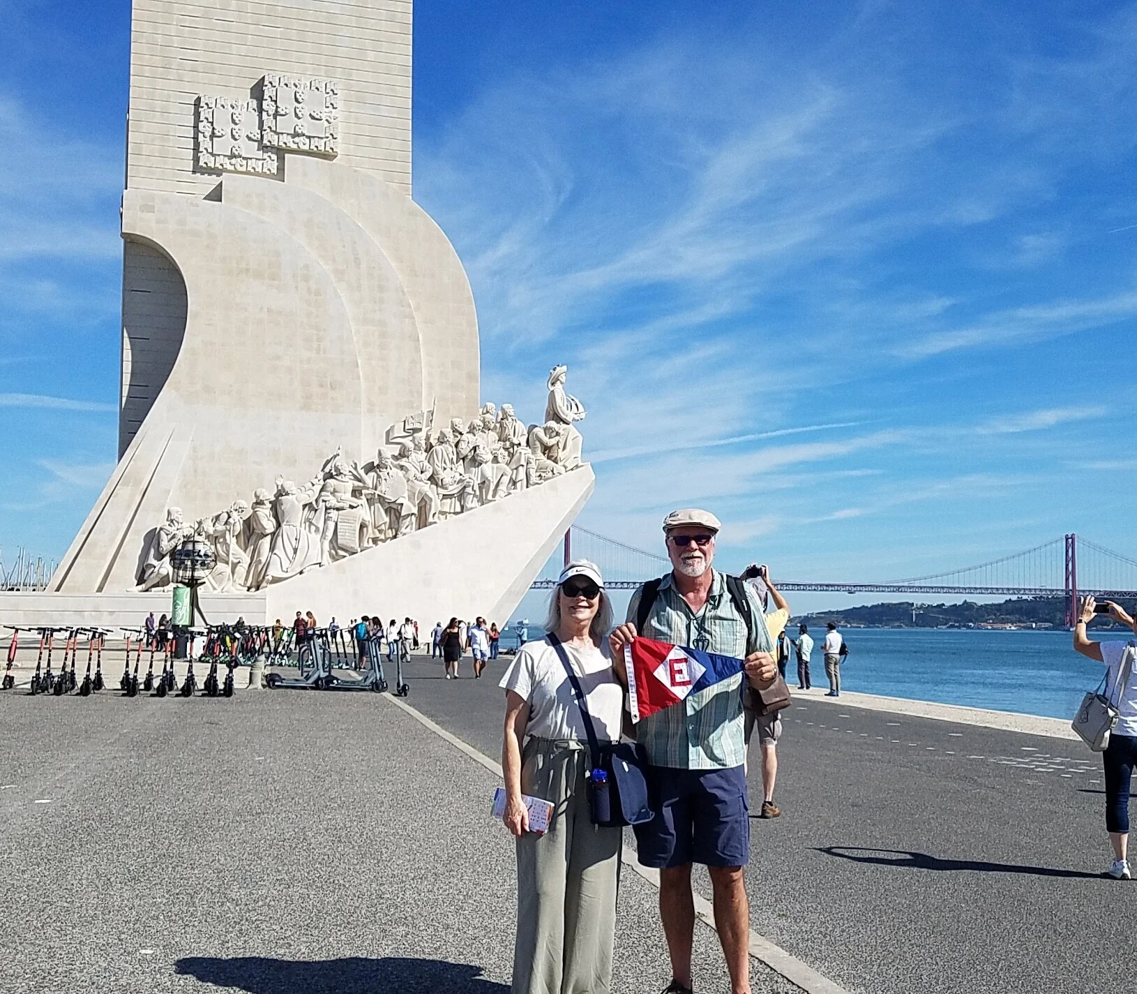 Linda and Murray show the colors in front of the Vasco de Gama Memorial in Lisbon, Portugal