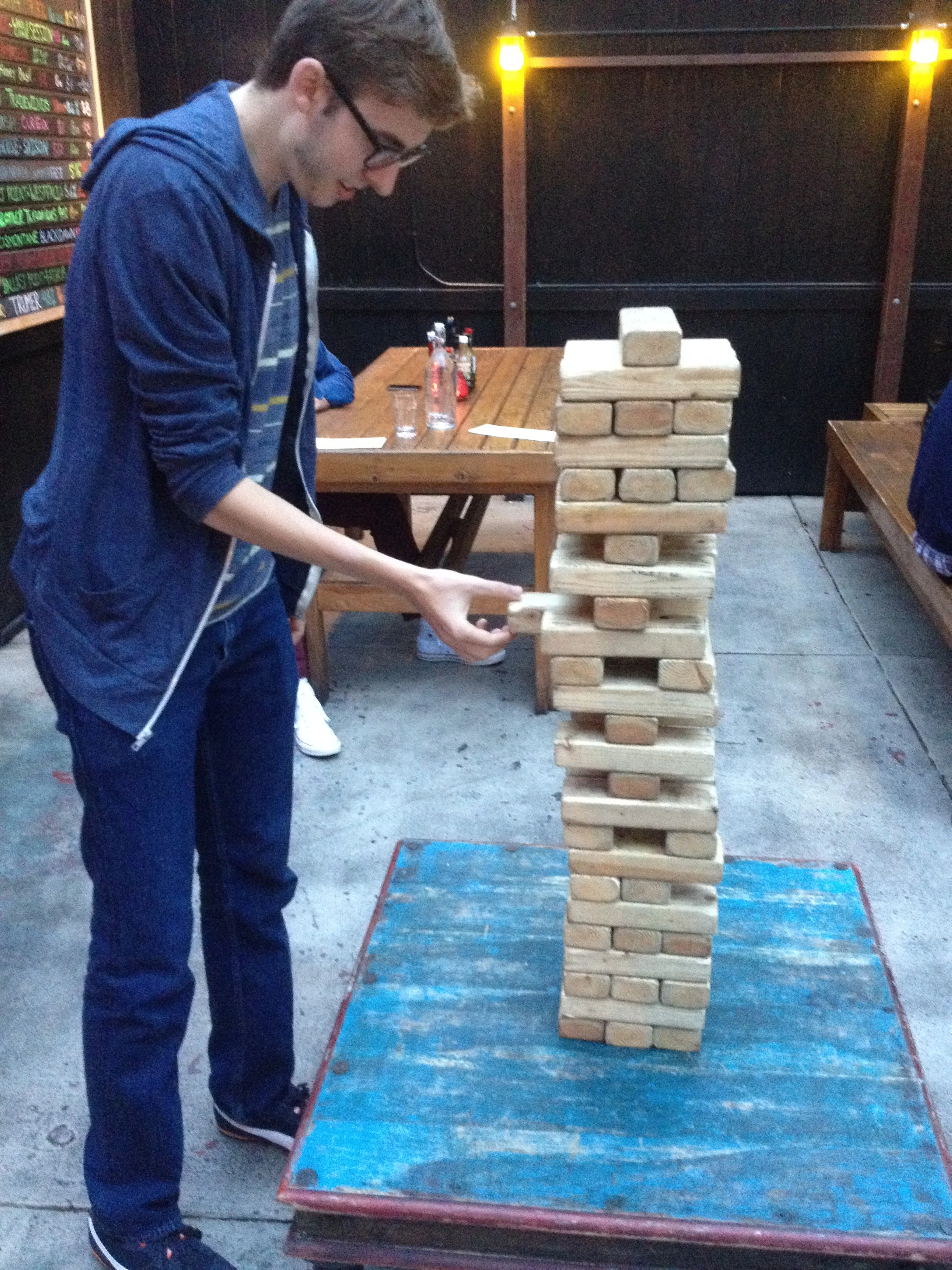 Colin playing a giant Jenga game at a restaurant