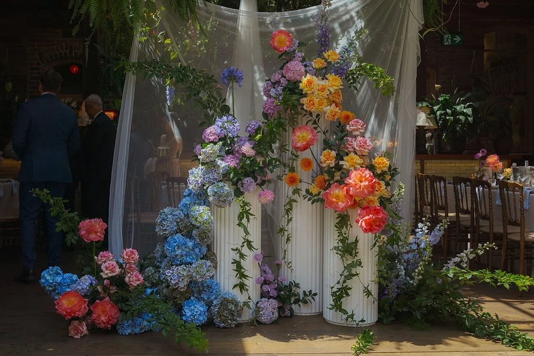 Julie and Bobby’s ceremony backdrop is a summer dream. Bright and colourful for a perfect summer wedding in The Atrium at the Grounds of Alexandria. 
Stunning plinth arrangements with soft draping that turns into an epic cake display. 
Colour