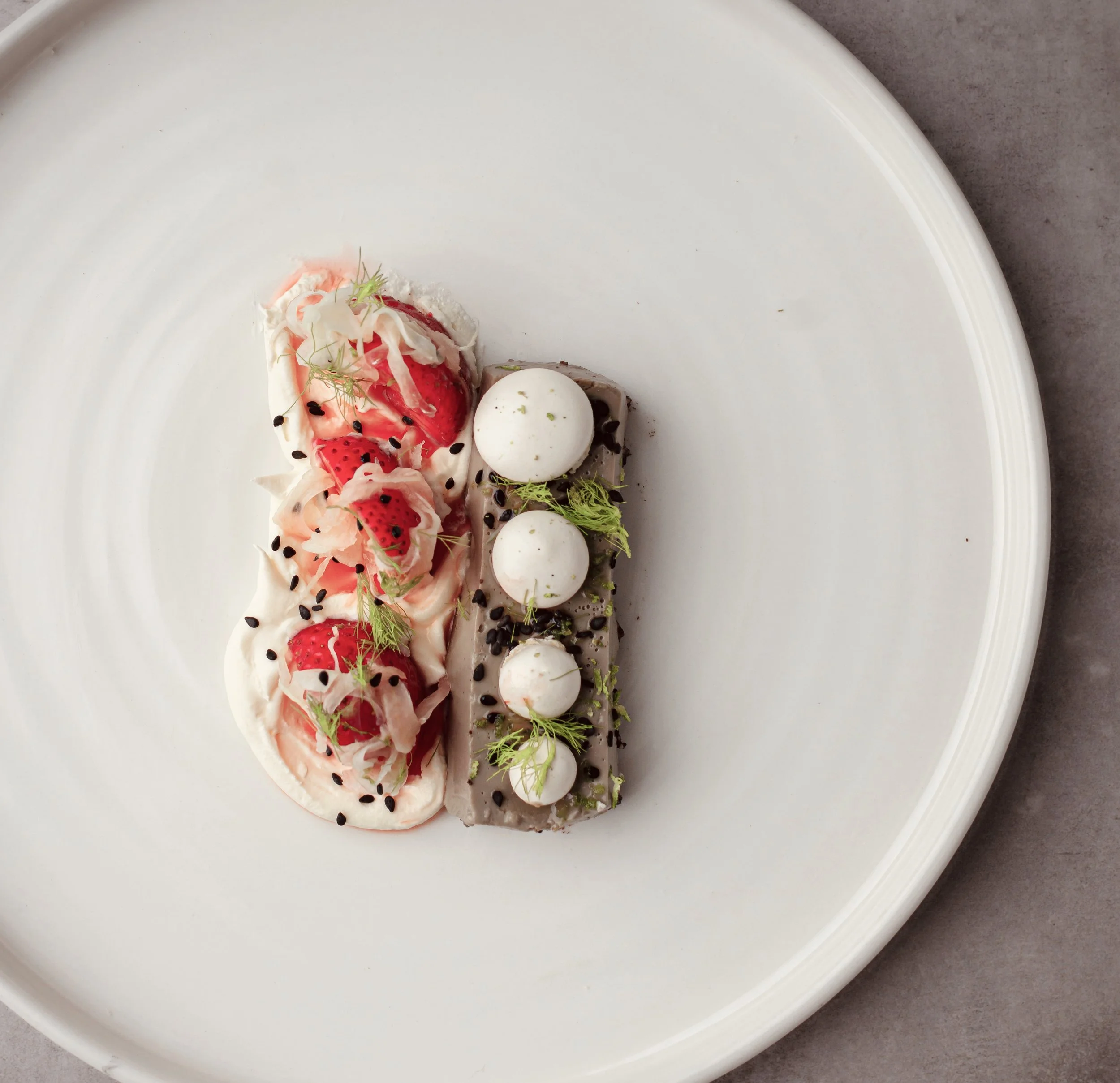 A dinner party dessert with strawberry, italian meringue, black sesame dacquoise