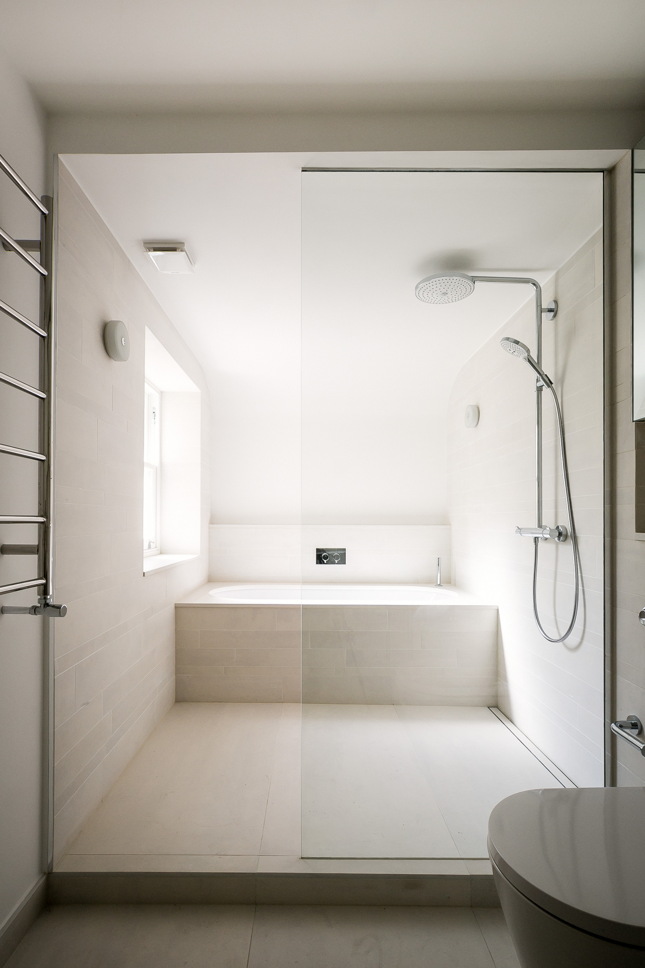 In the master bathroom porcelain tiles to the walls and floor create an airy wet room aesthetic. 