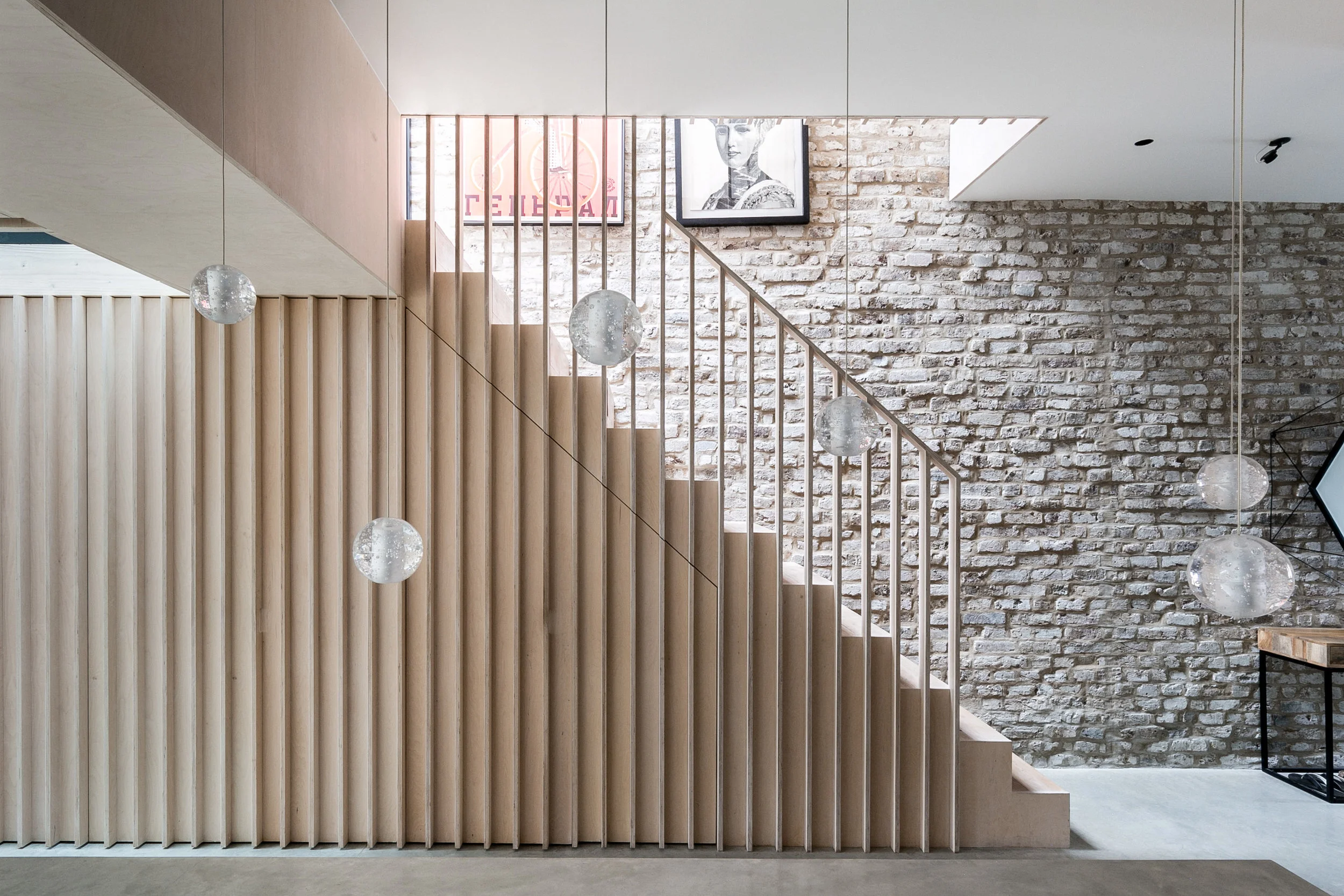 A plywood staircase with vertical slats leads to the first floor.