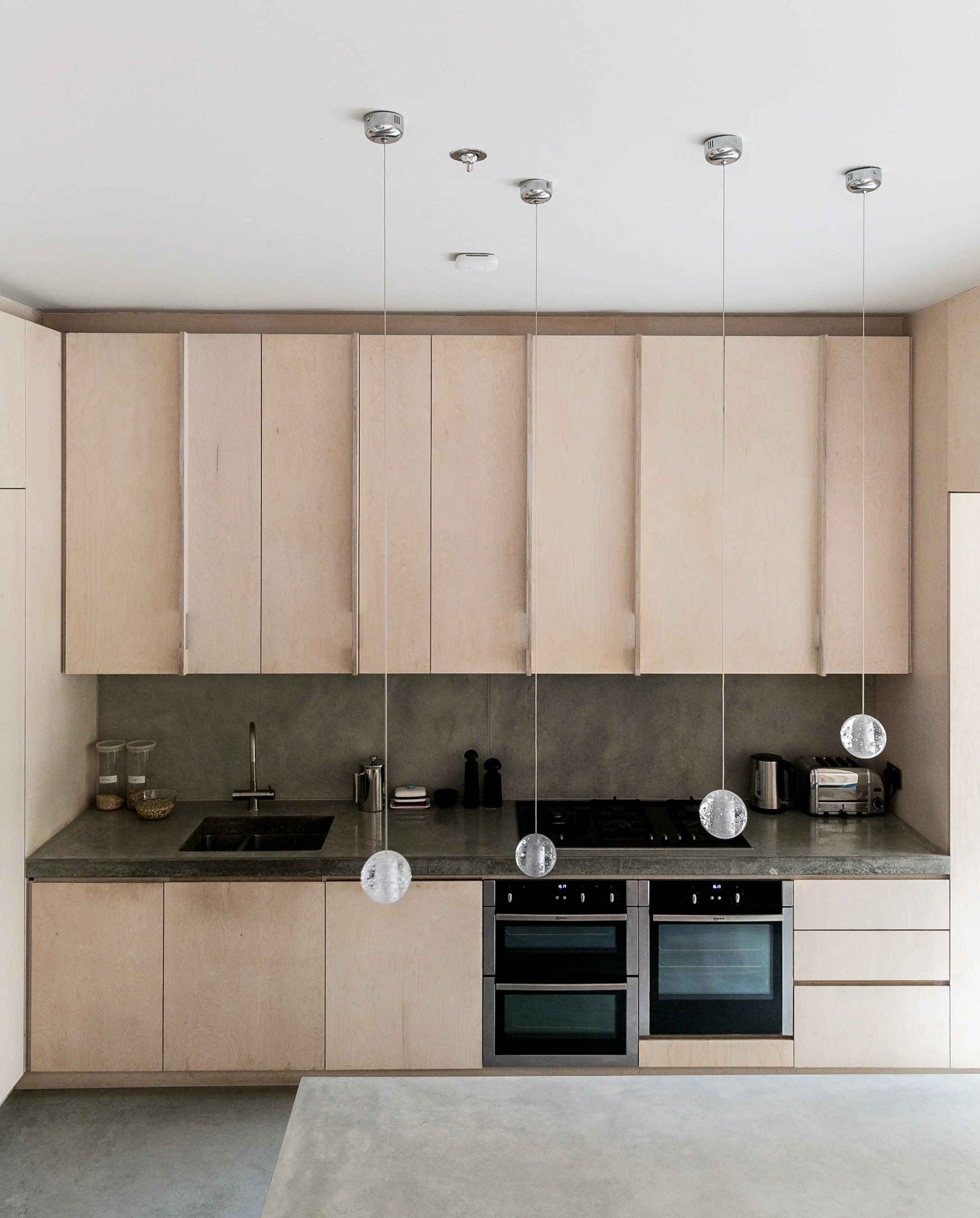 The kitchen is designed with plywood cabinets and integrated appliances.