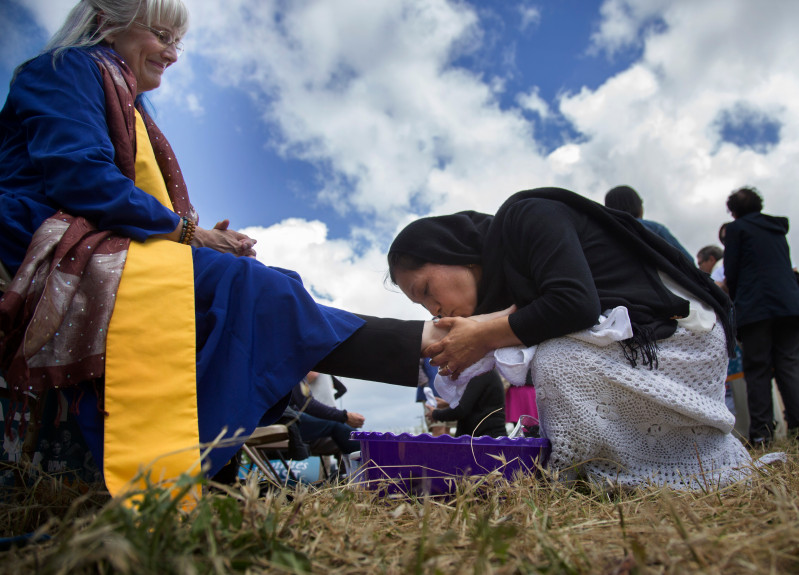 Minerva Rosas, of San Jose, kisses the foot of Rev. Nancy Palmer Jones as local activists wash the feet of immigrants and refugees and they return the favor on Holy Thursday outside the Immigration and Customs Enforcement facility in Morgan Hill, Calif., Thursday, April 13, 2017. PACT, which organized the event, said it is doing it to denounce the administration’s recent ICE raids and deportations. (Patrick Tehan/Bay Area News Group)