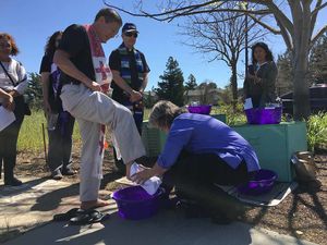 Reverend Wilma Jakobsen of St. Jude’s Episcopal church in Cupertino washes the feet of Father Jon Pedigo outside the U.S. Immigration and Customs Enforcement office in Morgan Hill March 29. - By Michael Moore