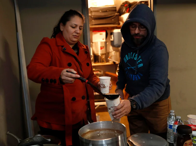 Mountain View, CA - DECEMBER 3: Resident Guadalupe Rosas, left, pours Donis Morales some hot chocolate during their meeting in a carport at their rent controlled apartment building along Rock St. in Mountain View, Calif., on Monday, Dec. 3, 2018. They meet every week. Mountain View city officials are considering a developer's proposal to raze 20 rent-controlled, affordable apartments and replace them with 15 new, luxury town houses. (Nhat V. Meyer/Bay Area News Group)