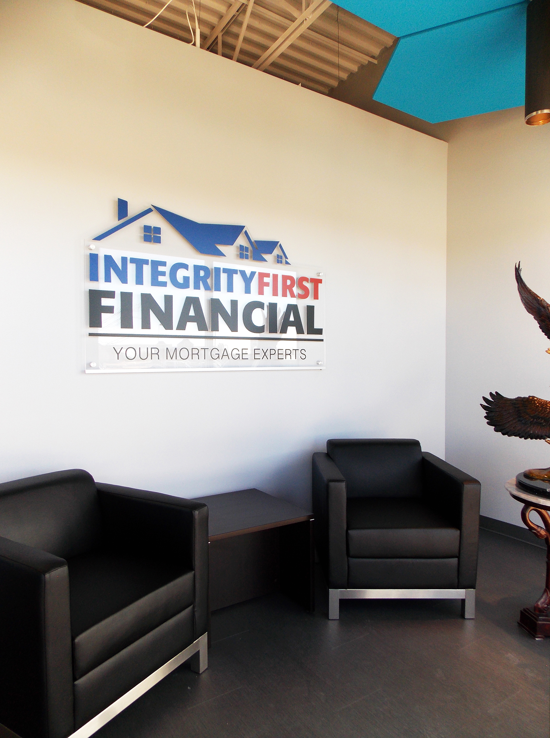 The entrance to Integrity features an efficient seating area with plenty of natural light and a large, LED backlit acrylic cut sign created by Layer Nine Design . The open ceiling is visible above the walls to make the entire office feel more spacious.