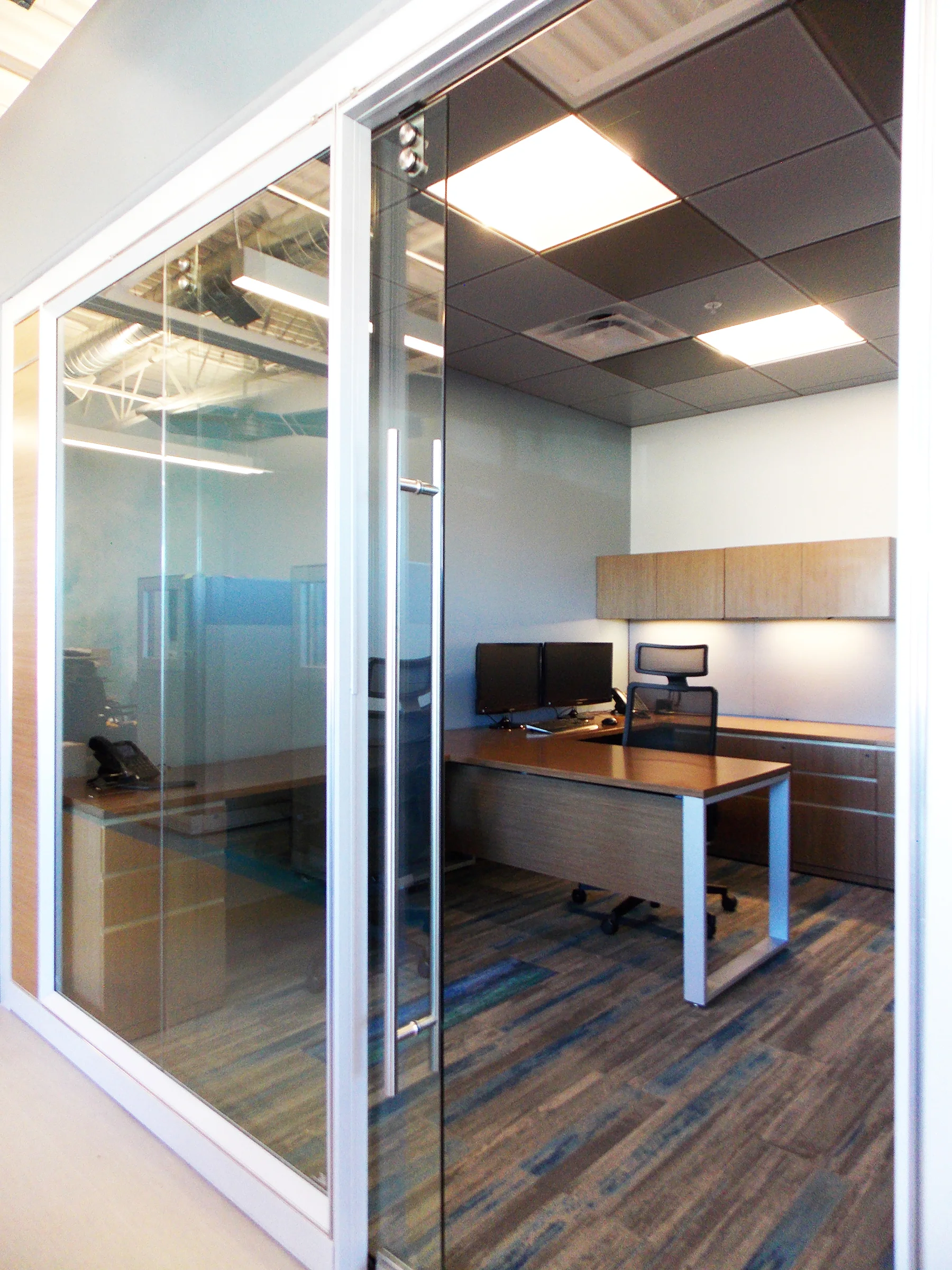 This aluminum and glass architectural wall system provided by Office Interiors Denver separates the private offices and conference room from the open work area and cubicles. Natural light from the storefront floods across the space into the private offices so that everyone can take full advantage of the daylight.
