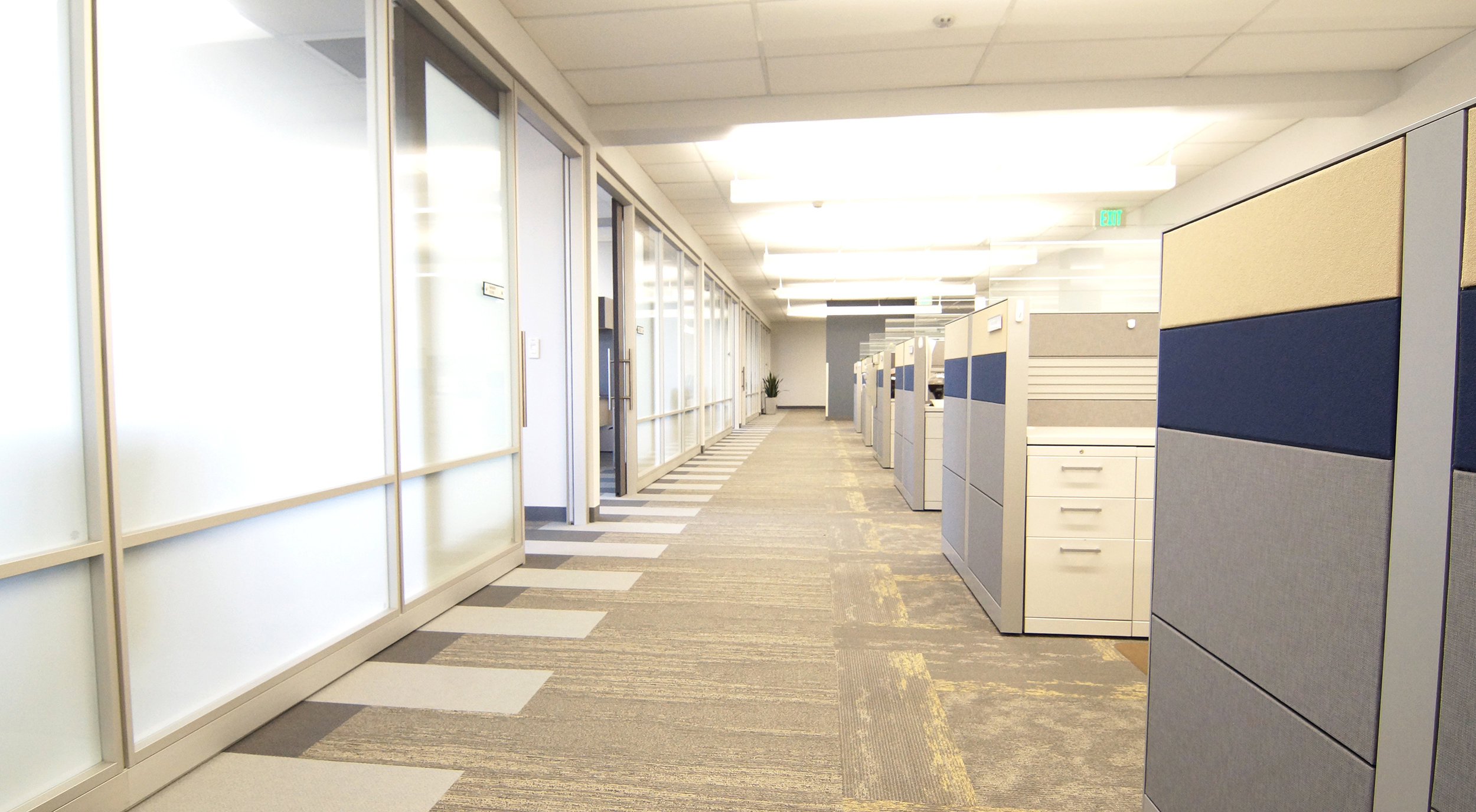 Throughout the space, offices with glass fronts line the exterior of the floors, allowing natural light to filter into the open office interior where the workstations are installed. The carpet pattern is comprised of the three styles of Mohawk’s Iconic Earth collection along with accents of blue installed in a “zipper” pattern underneath the architectural wall system, weaving in and out of the private offices.