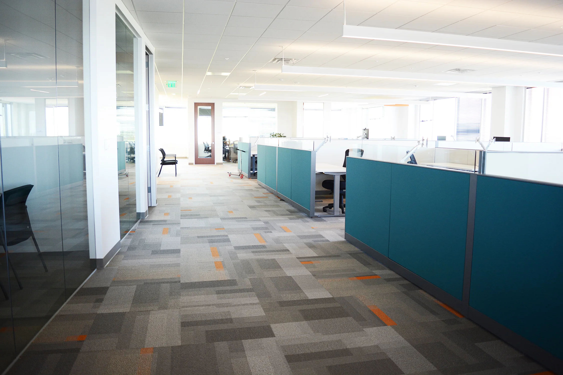 From the beginning, the approach to space planning was to provide all employees access to natural light and the mountain views. This was achieved by placing private glass front offices on the interior and utilizing workstations with glass privacy screens to allow light to filter within the open office. The teal end panels paired with Patcraft’s Color Pop carpet add the final touch of branding needed throughout the office.