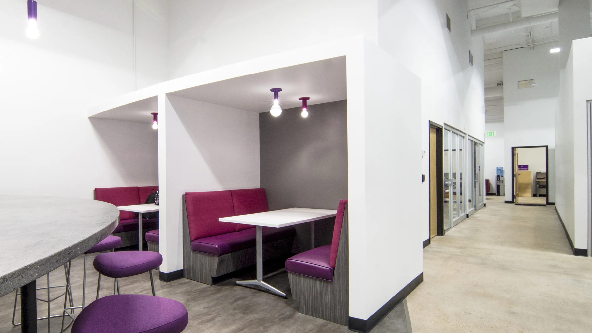 At the break room, Solderworks wanted to not just provide an area for storing and heating up lunches and snacks but an area with a sense of place. Additional tables and chairs were placed adjacent to the area and private booths were added. The owner liked the idea of a restaurant feel and the booths allow for semi-private meetings. Power access was added above the tables and small televisions will be installed to allow for each booth to become a rentable meeting space.