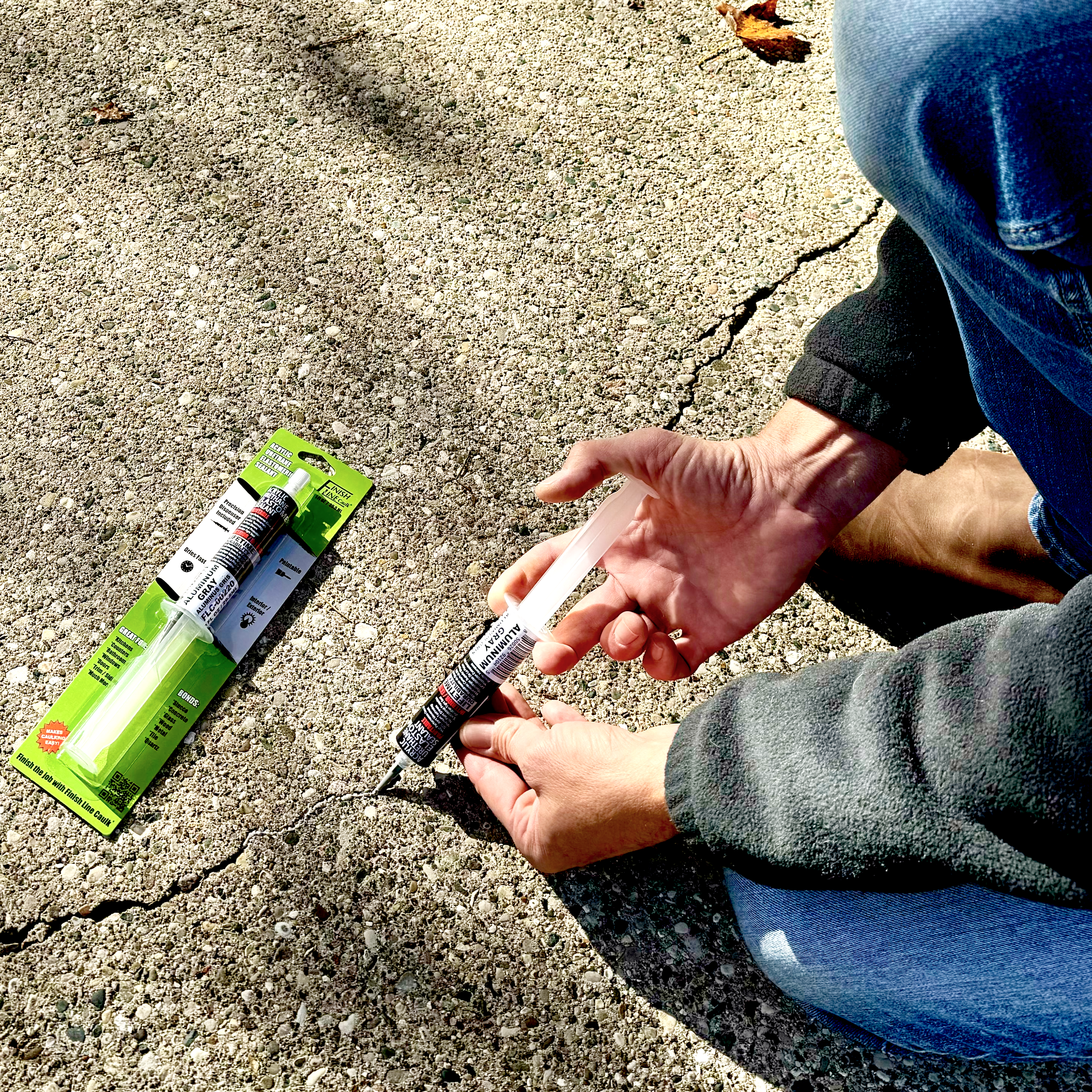Applying precision caulk to a crack in a concrete slab using a Finish Line Caulk applicator for controlled, clean placement.