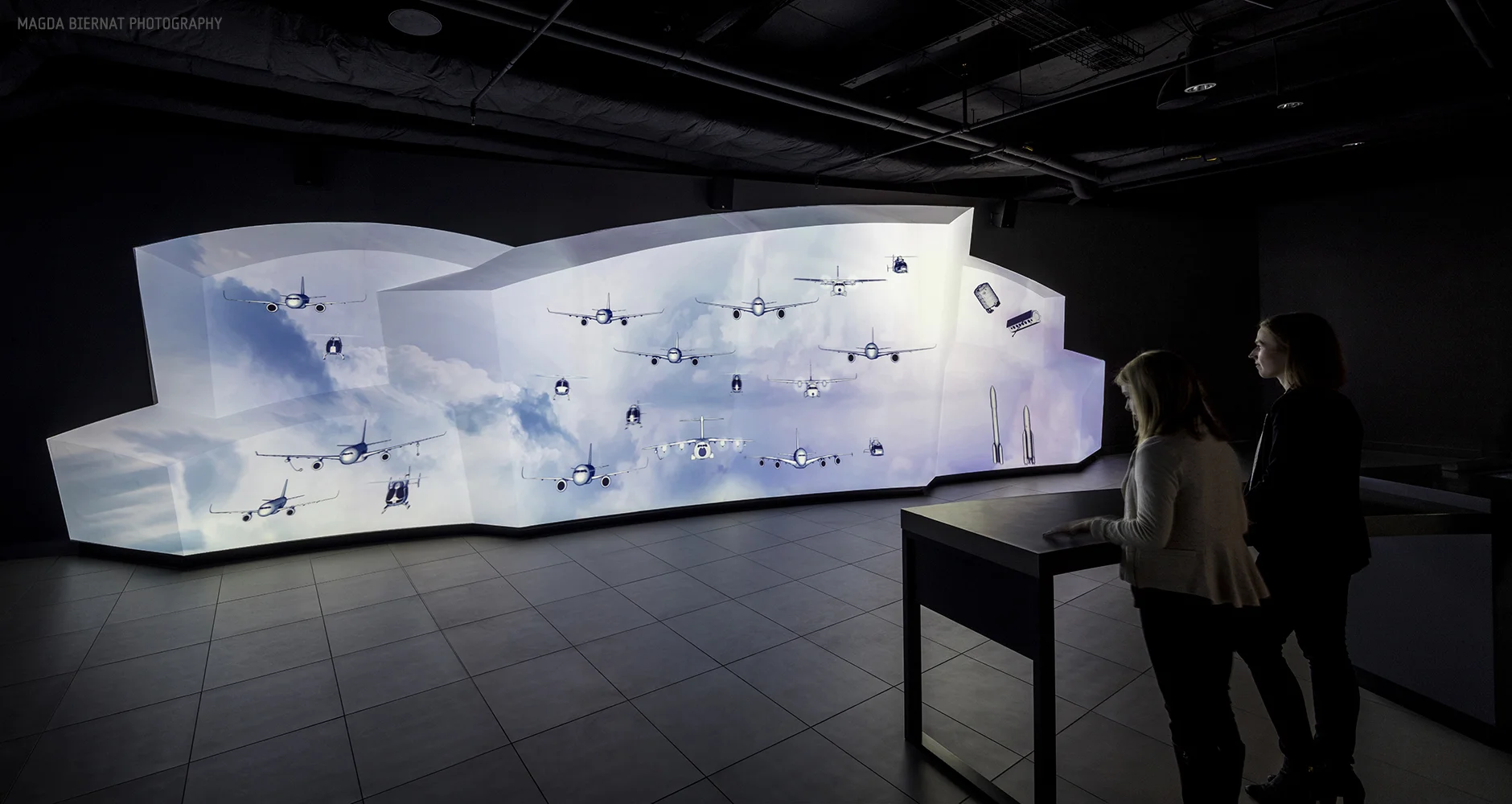 Beyond a secret opening revealed by a moving wall, visitors encounter a 40-foot-long Fleet Wall. When activated, projected imagery and interactive 3D models animate across the sculpted surface. Leveraging depth, scale and motion, visitors are immers…