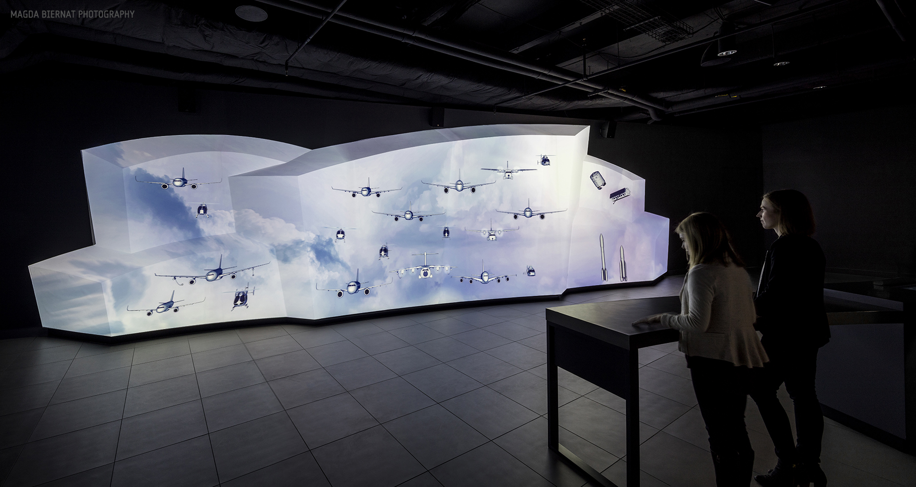 Beyond a secret opening revealed by a moving wall, visitors encounter a 40-foot-long Fleet Wall. When activated, projected imagery and interactive 3D models animate across the sculpted surface. Leveraging depth, scale and motion, visitors are immersed in a one-of-a-kind look at the breadth of commercial, helicopter, defense and aerospace products.