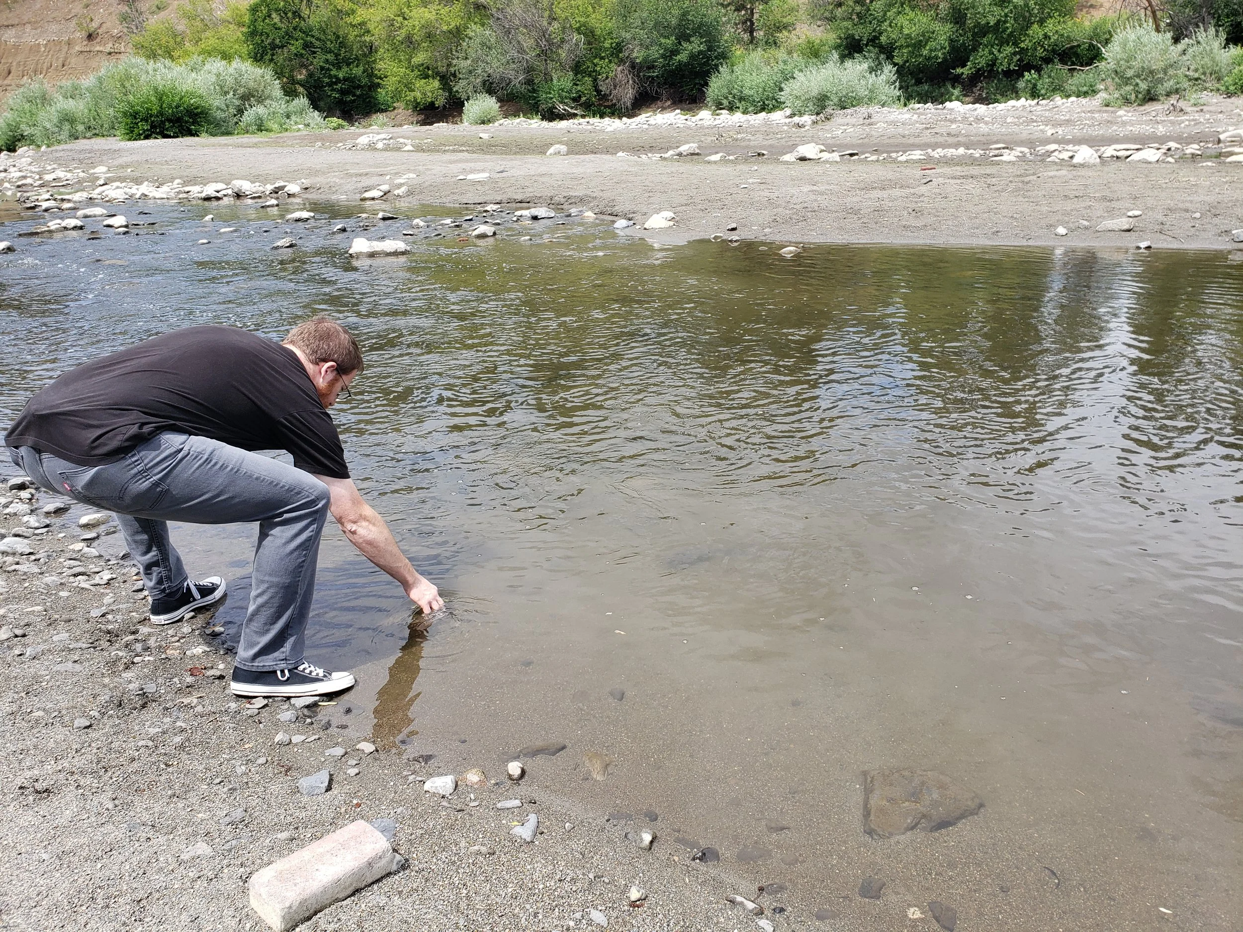 Dillon Wilke takes a water sample for E. coli at Hangman Creek.