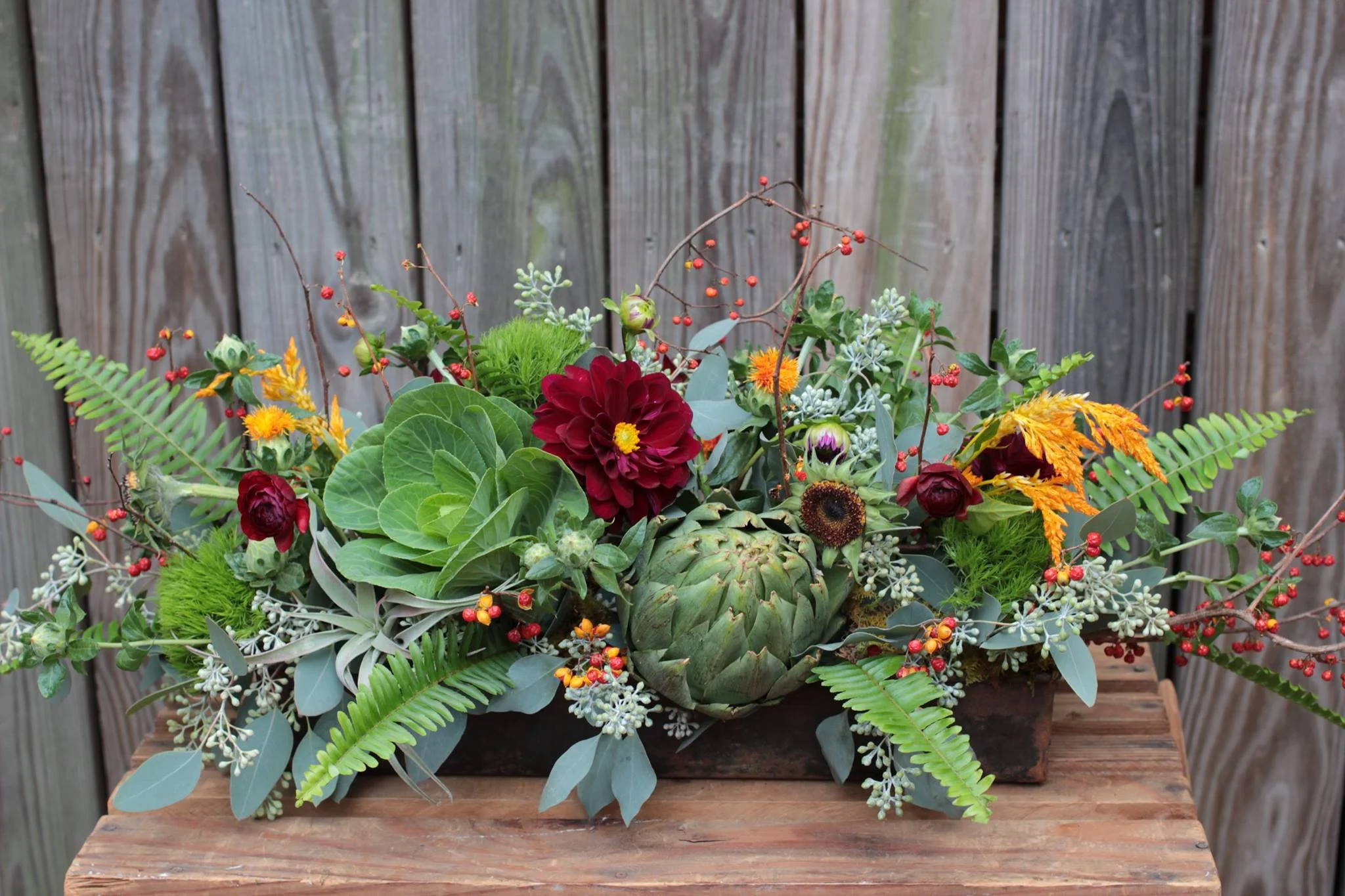 An arrangement featuring artichoke, cabbage, bittersweet, dahlias among others.