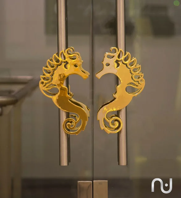Deema Oman's logo executed in brass finish and used as door handles.