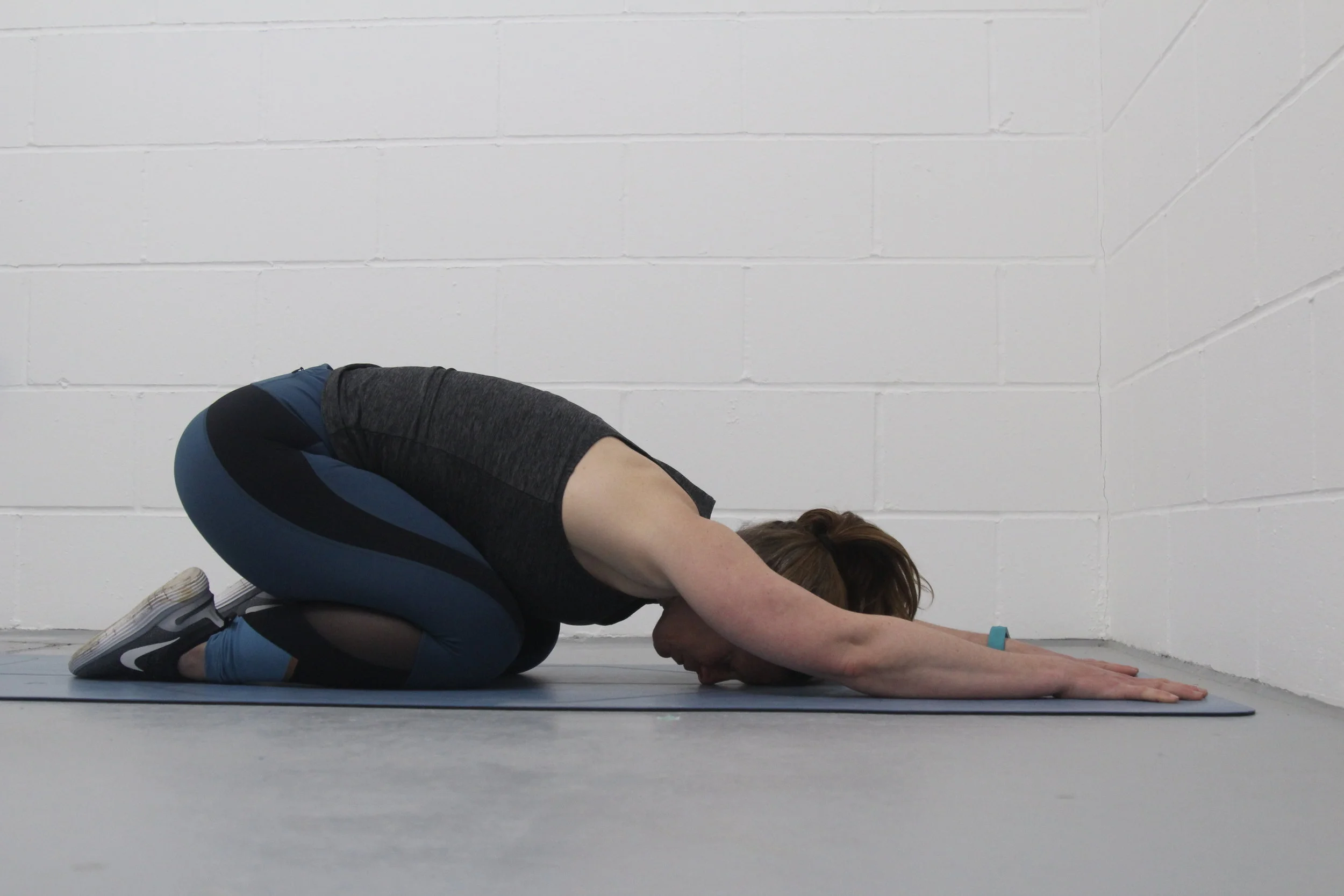 In a kneeling position, sit back on your feet, place your hands out in front of you and try to get your glutes to touch your feet.