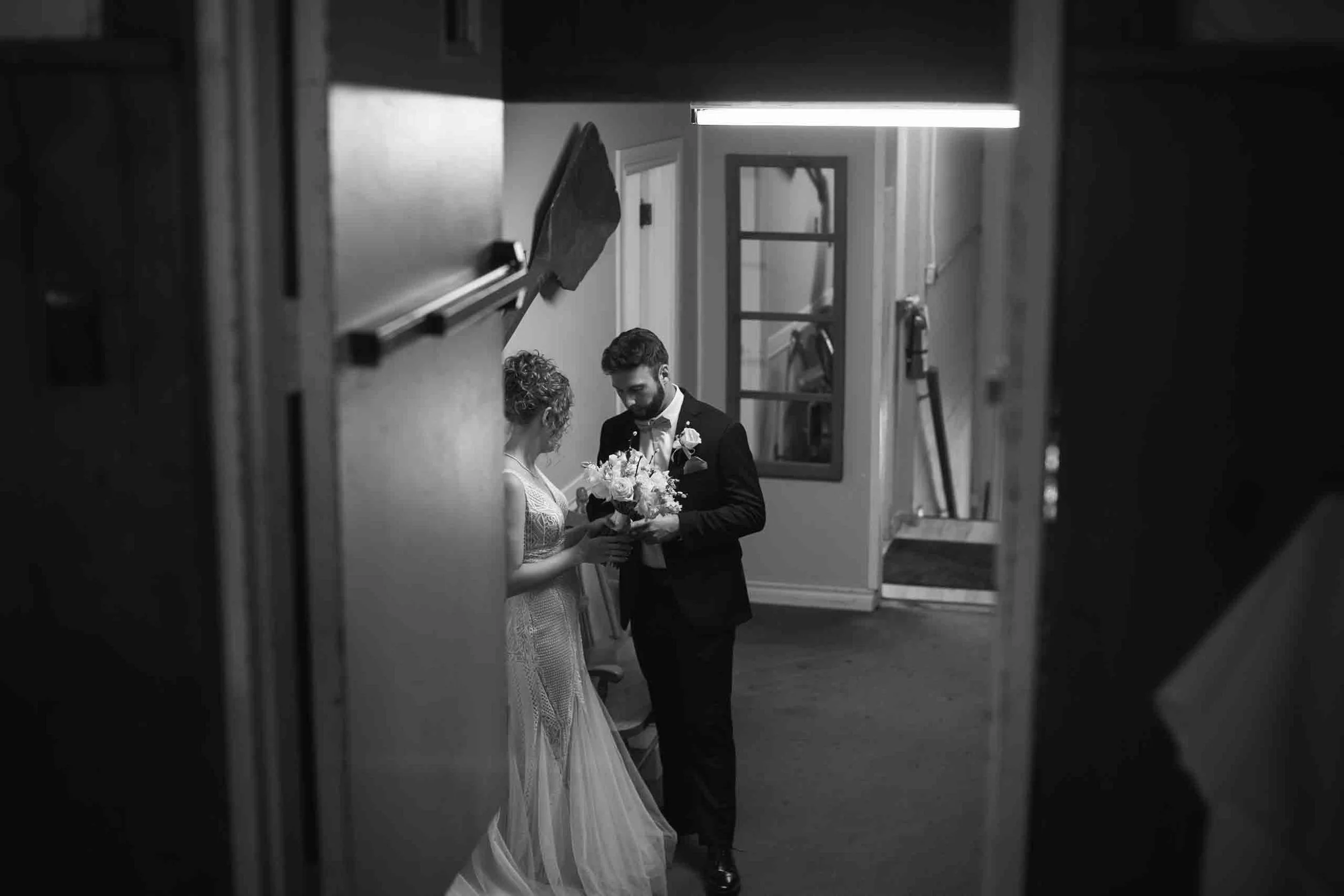 Black and white wedding photo of bride and groom getting ready for their wedding dinner reception.