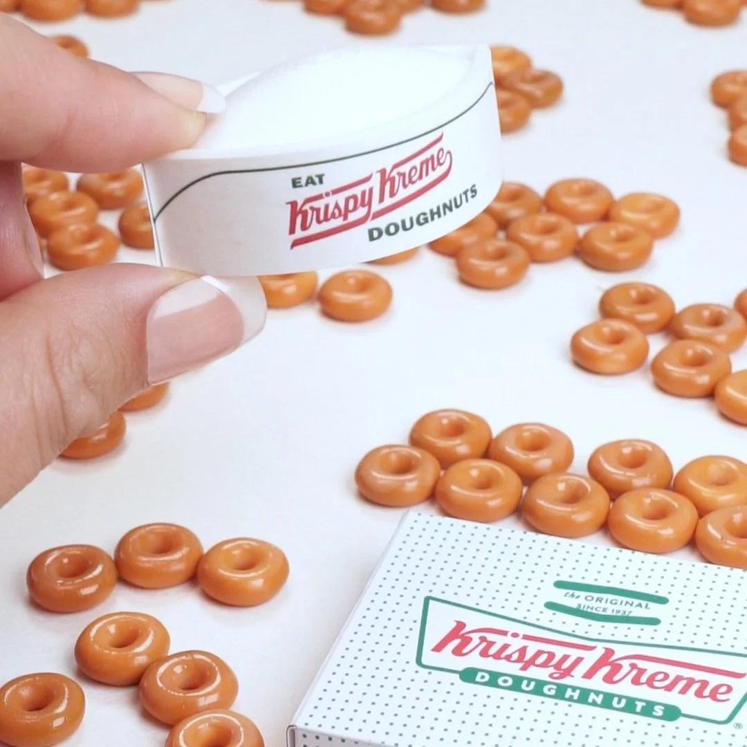 A hand holds a miniature krispy kreme hat