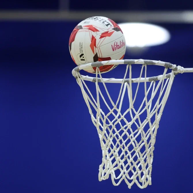 A volleyball going into a basketball hoop net.