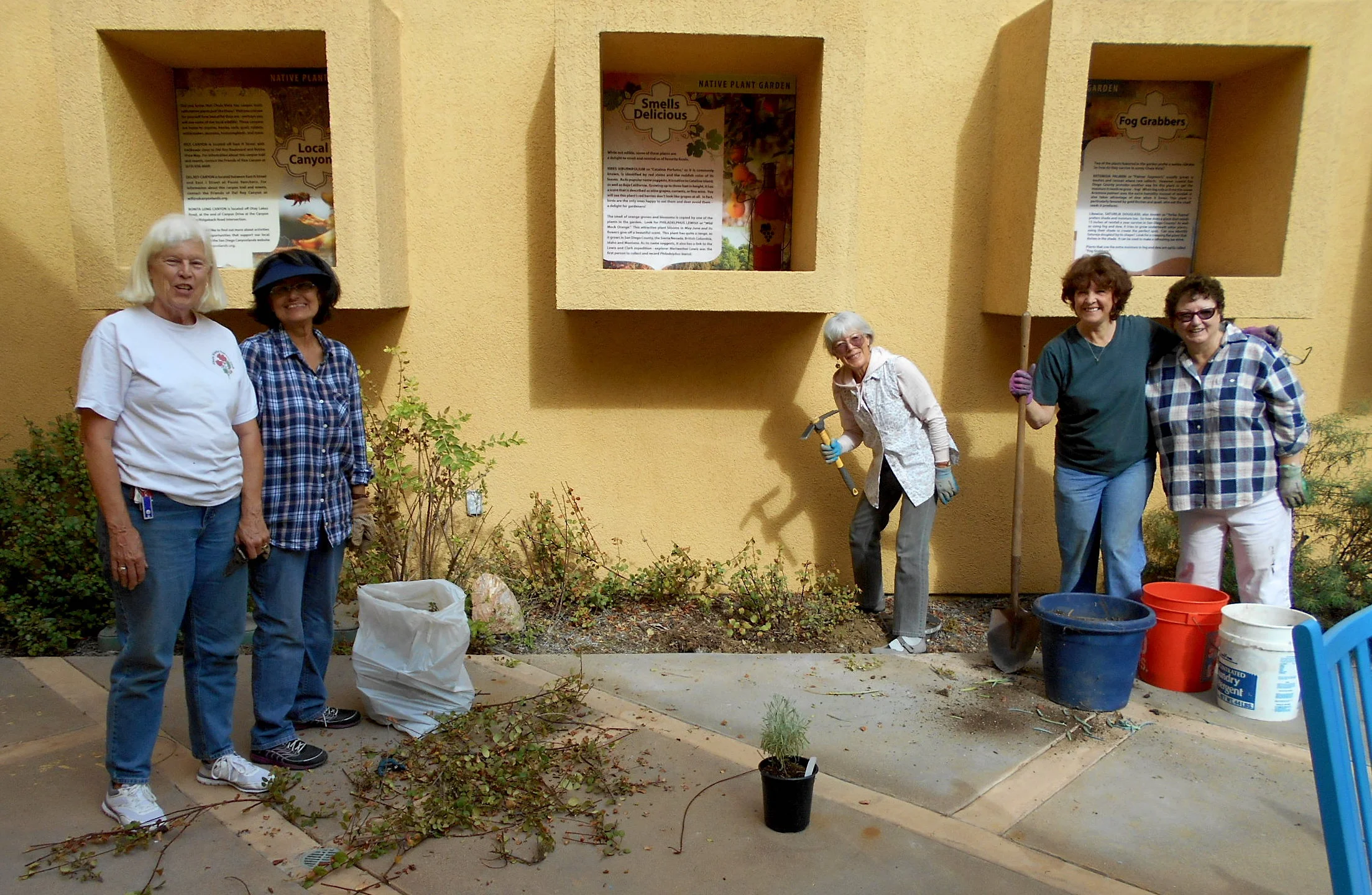 (L to R): Chris, Betty, Kay, Joan, and Emily plant and primp. The boxes over the plants have beautiful information posters.