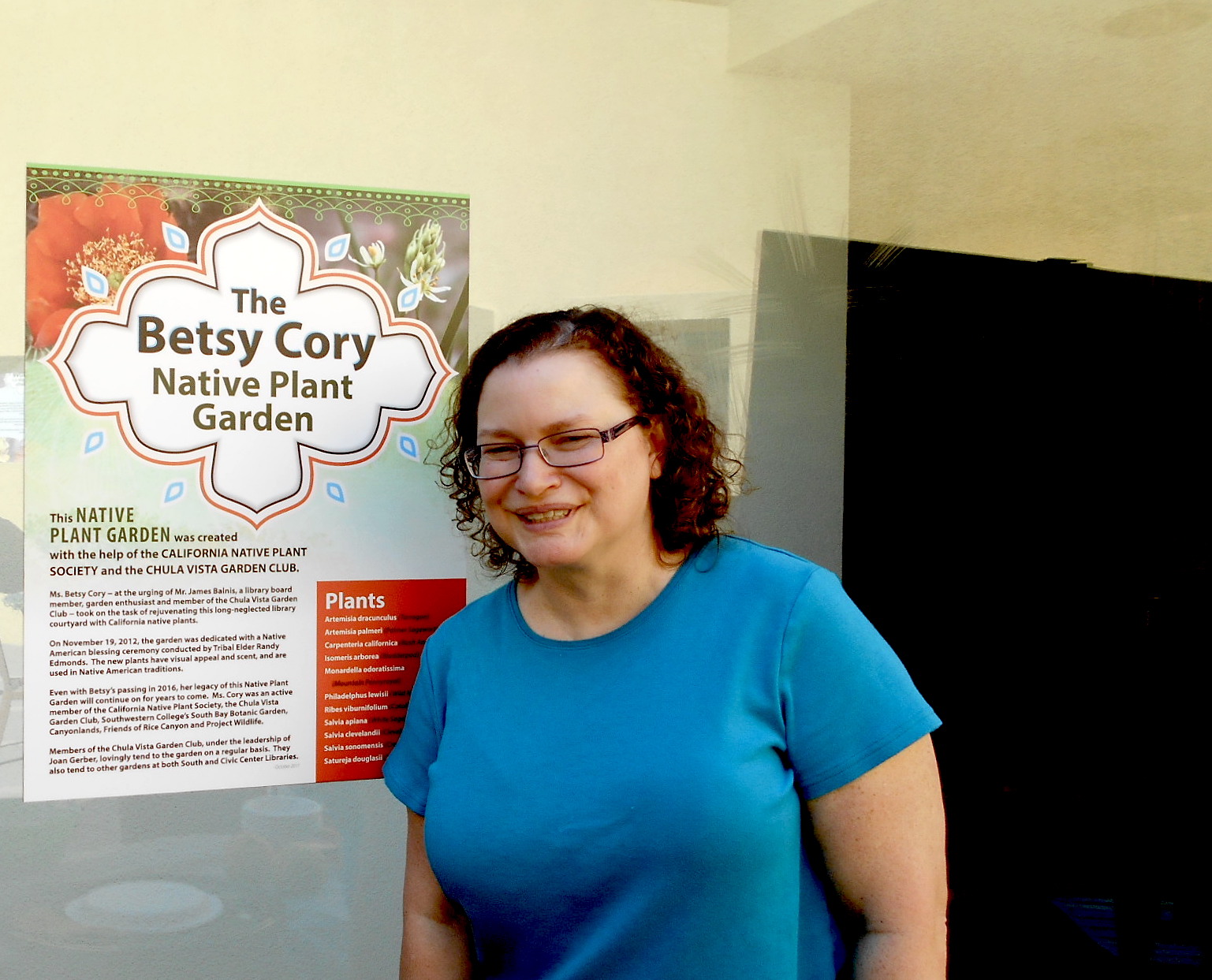 Robin, one of Betsy Cory's daughters, next to the Garden's sign.