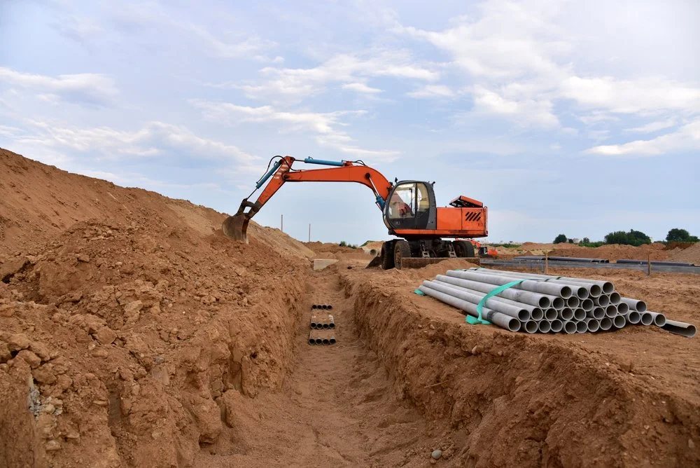 Excavator covering pipes with soil