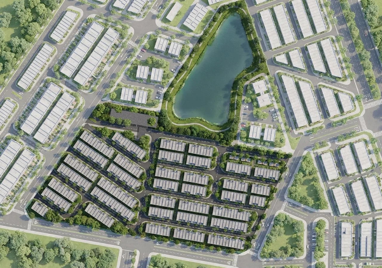 Aerial view of a residential community with neatly arranged houses, roads, and a central pond surrounded by green landscaping.
