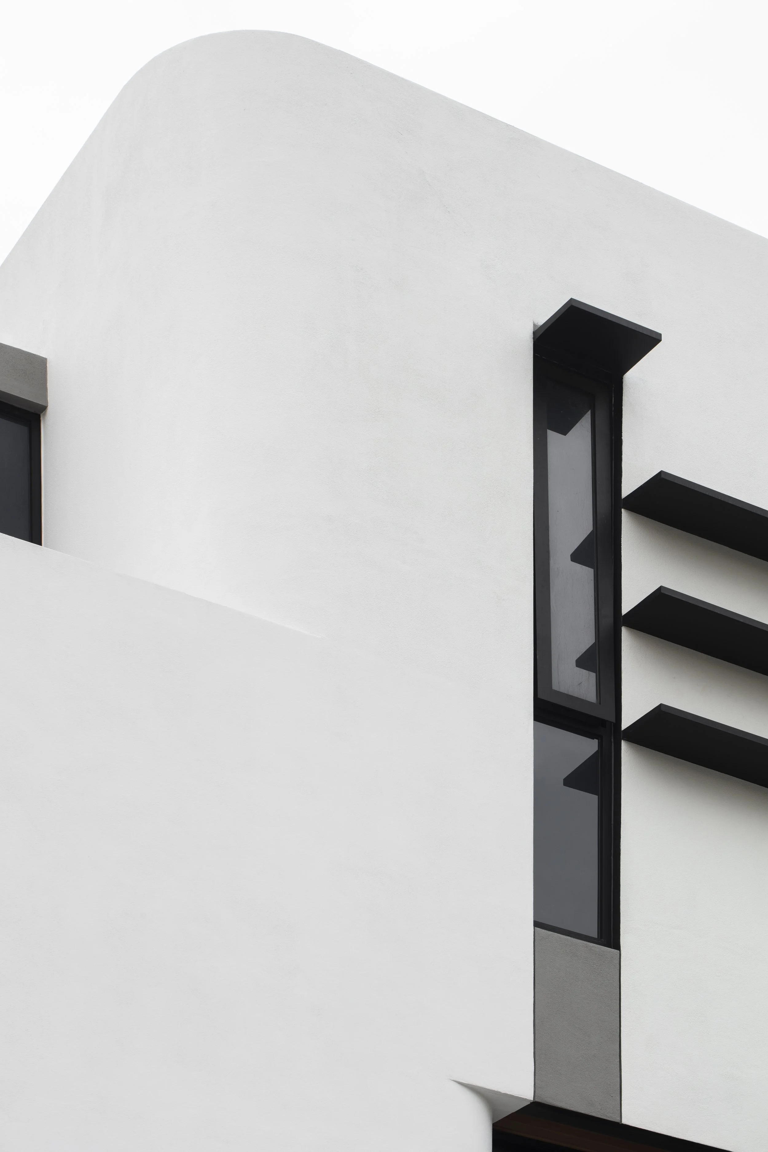 Close-up of a modern white building with black accents and large windows.