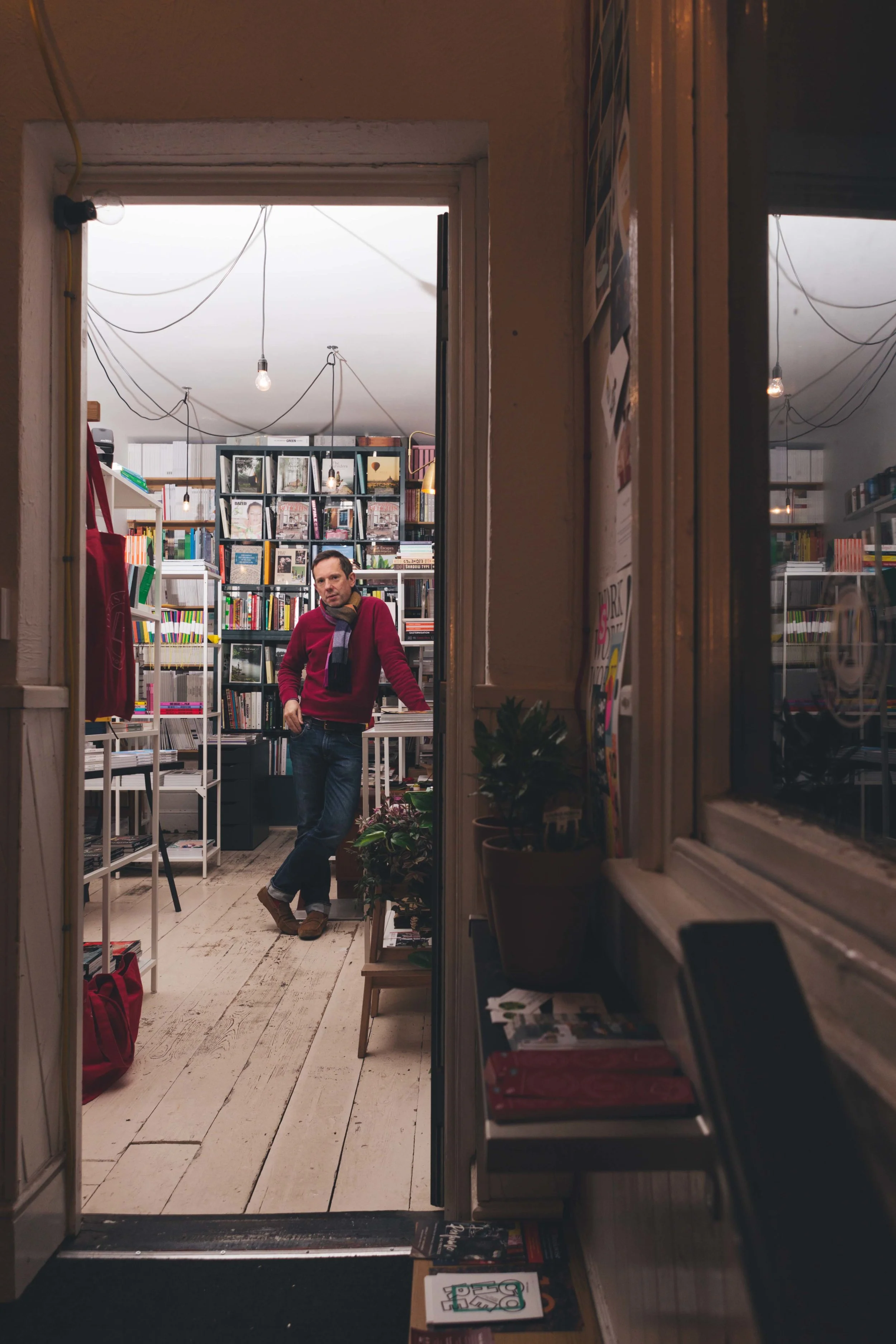 man in bookshop doorway, illuminated and lit up and surrounded by books 