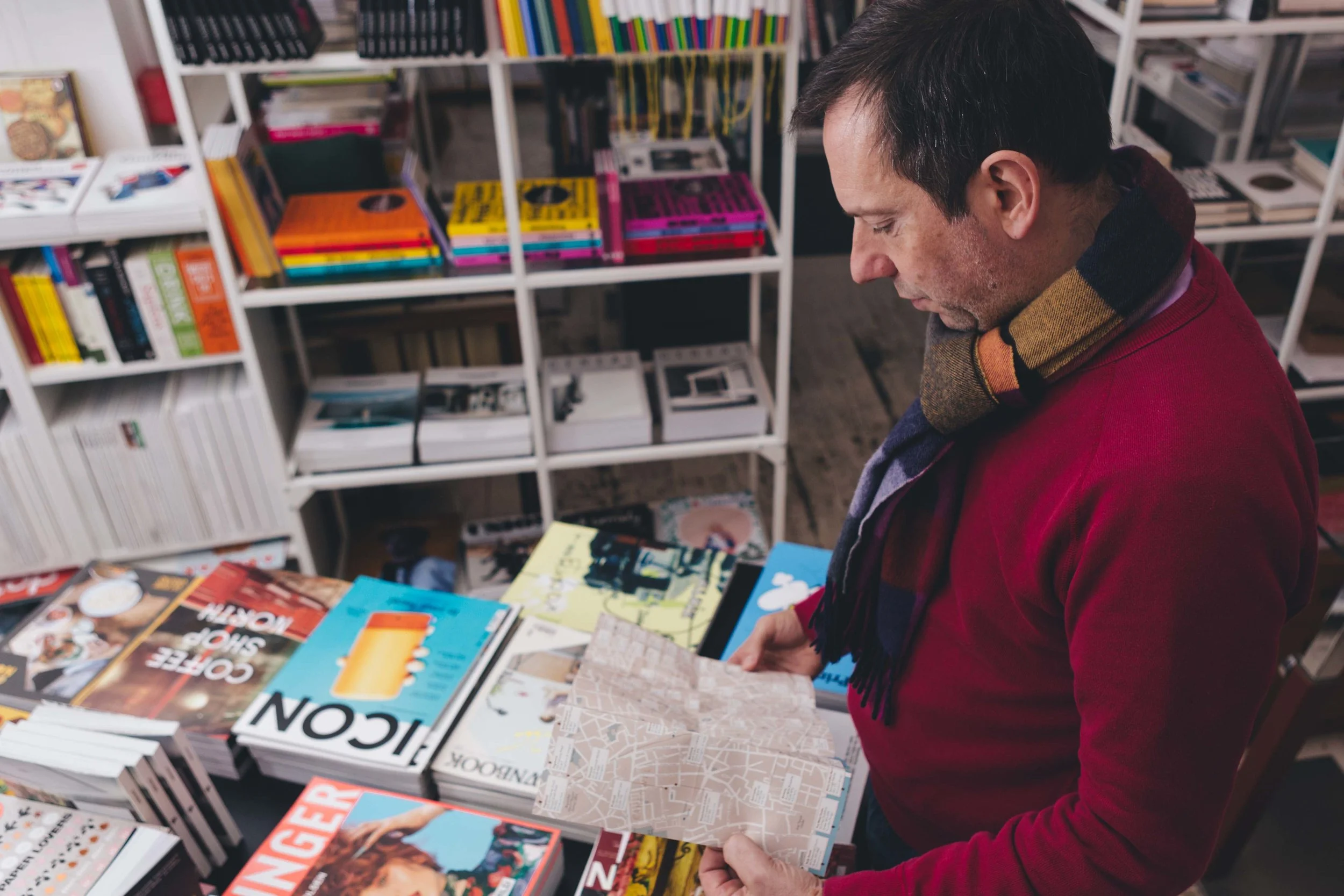 book shop filled with colourful books, with man looking at map in the forefront