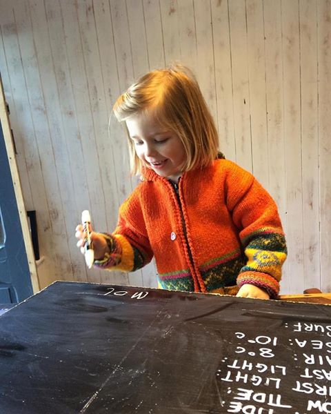 Mollie Mae writing up the surf report for The Green Room Surf School window