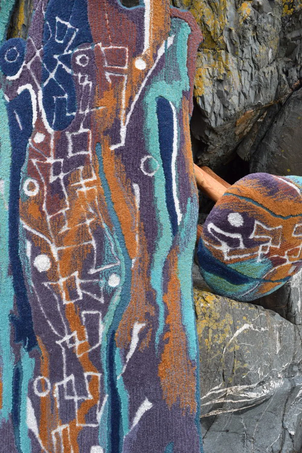 Colorful abstract rock art painted on large stones and rocks outdoors.