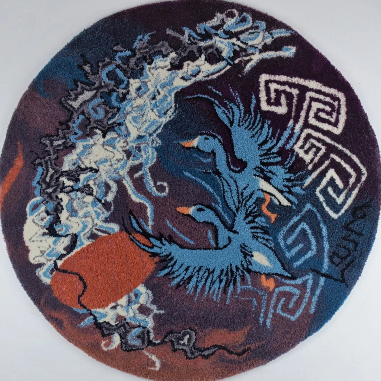 A round rug featuring rivers, an egg like sun or moon, and stylized blue white fronted geese, set against a dark background with celtic geometric patterns.