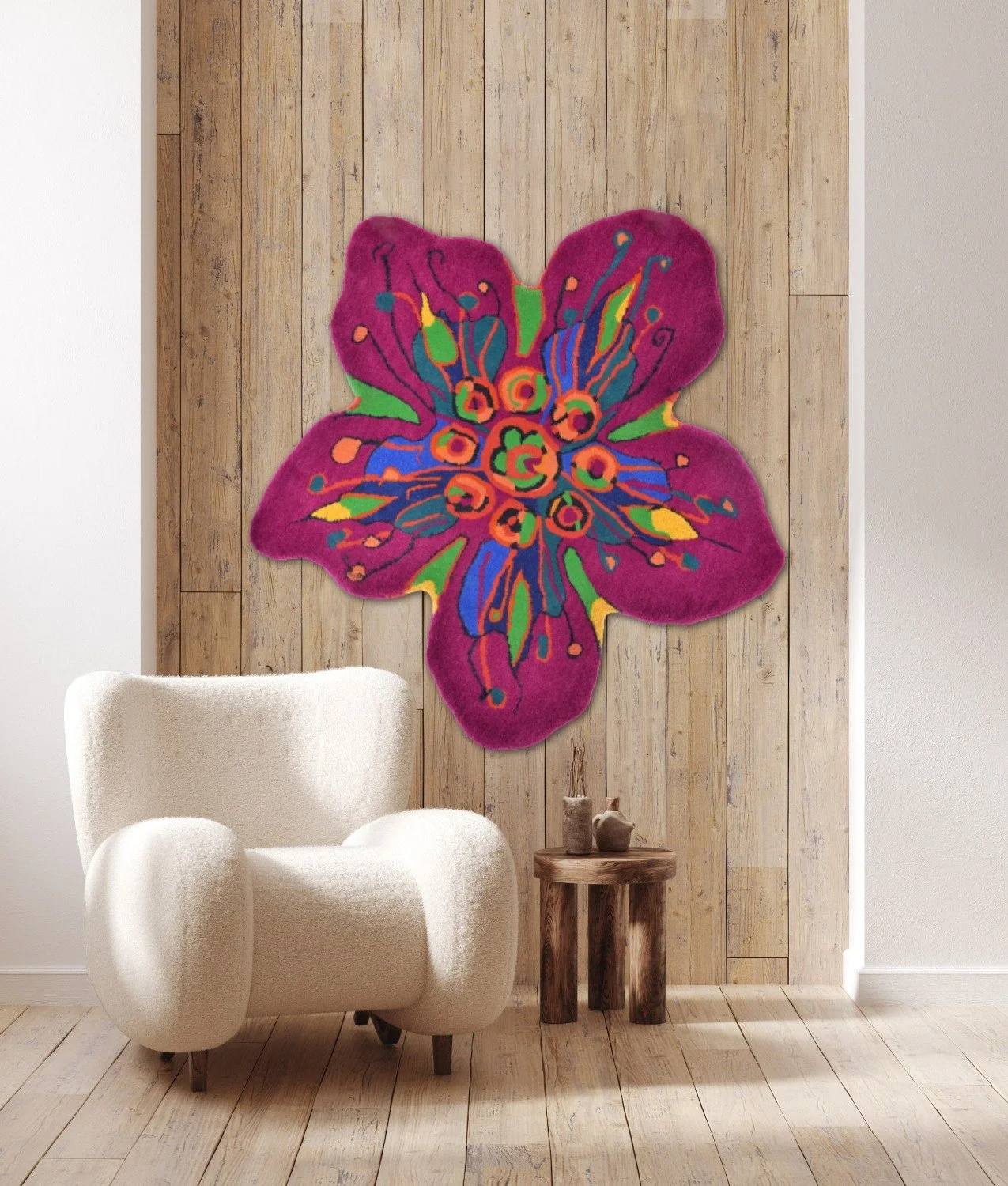 Decorative floral-shaped rug with bright pink, green, yellow, blue, and orange colors hangs on a wooden wall in a modern living space. A white armchair and a small wooden side table with candles are in front of the rug.